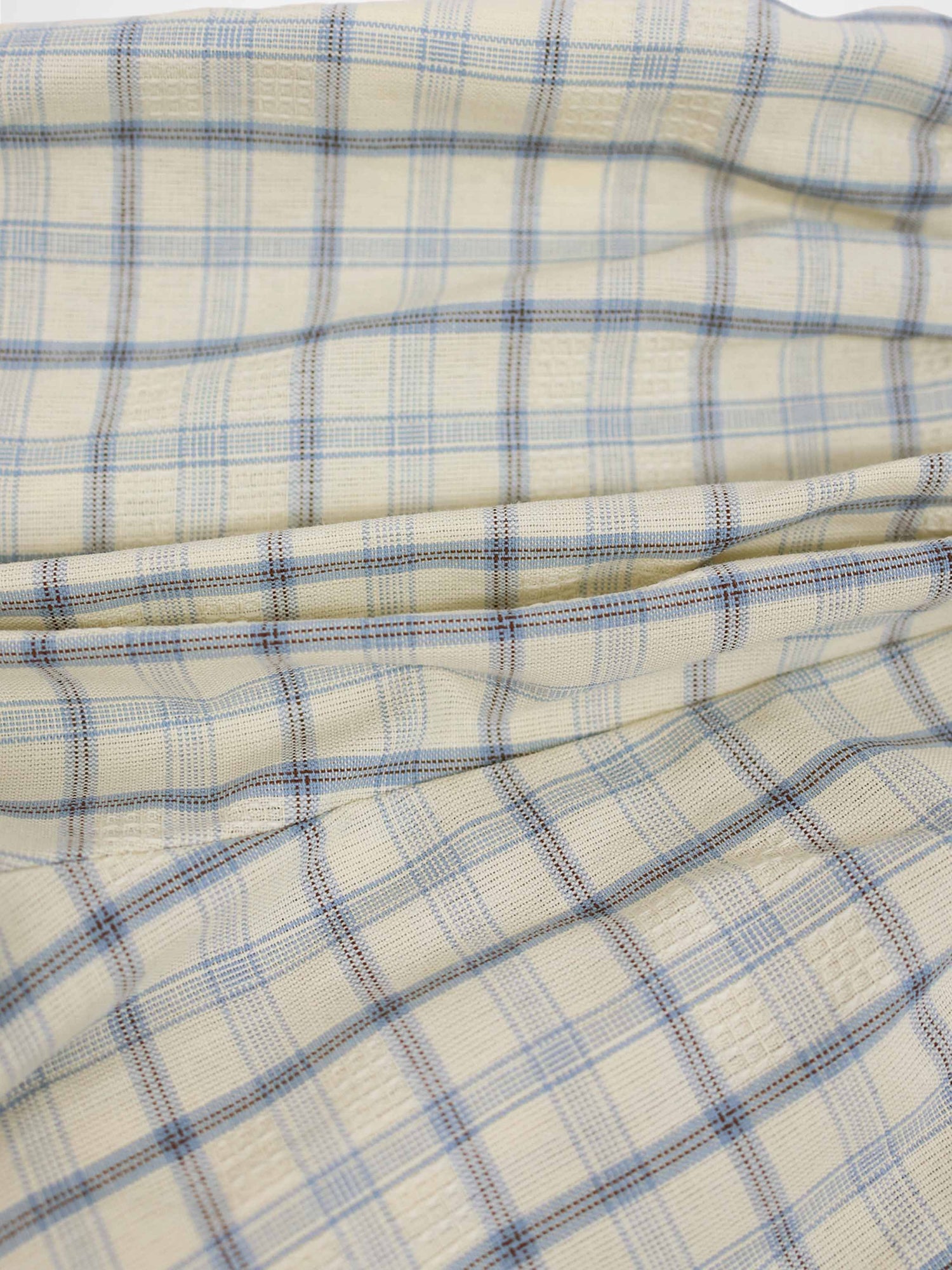Cream plaid fabric for shorts with light blue and brown lines, soft woven texture.