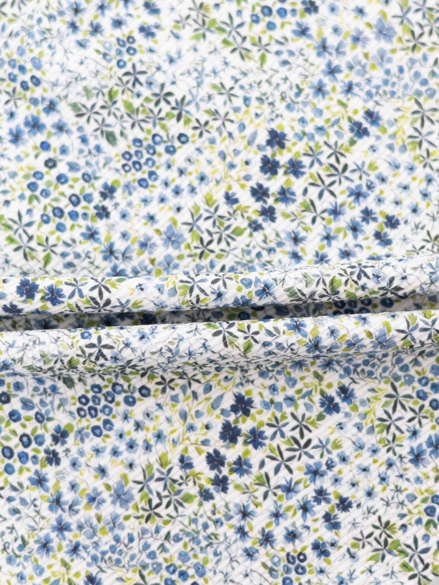 Blue floral pajama fabric with blue and green flowers on white background.