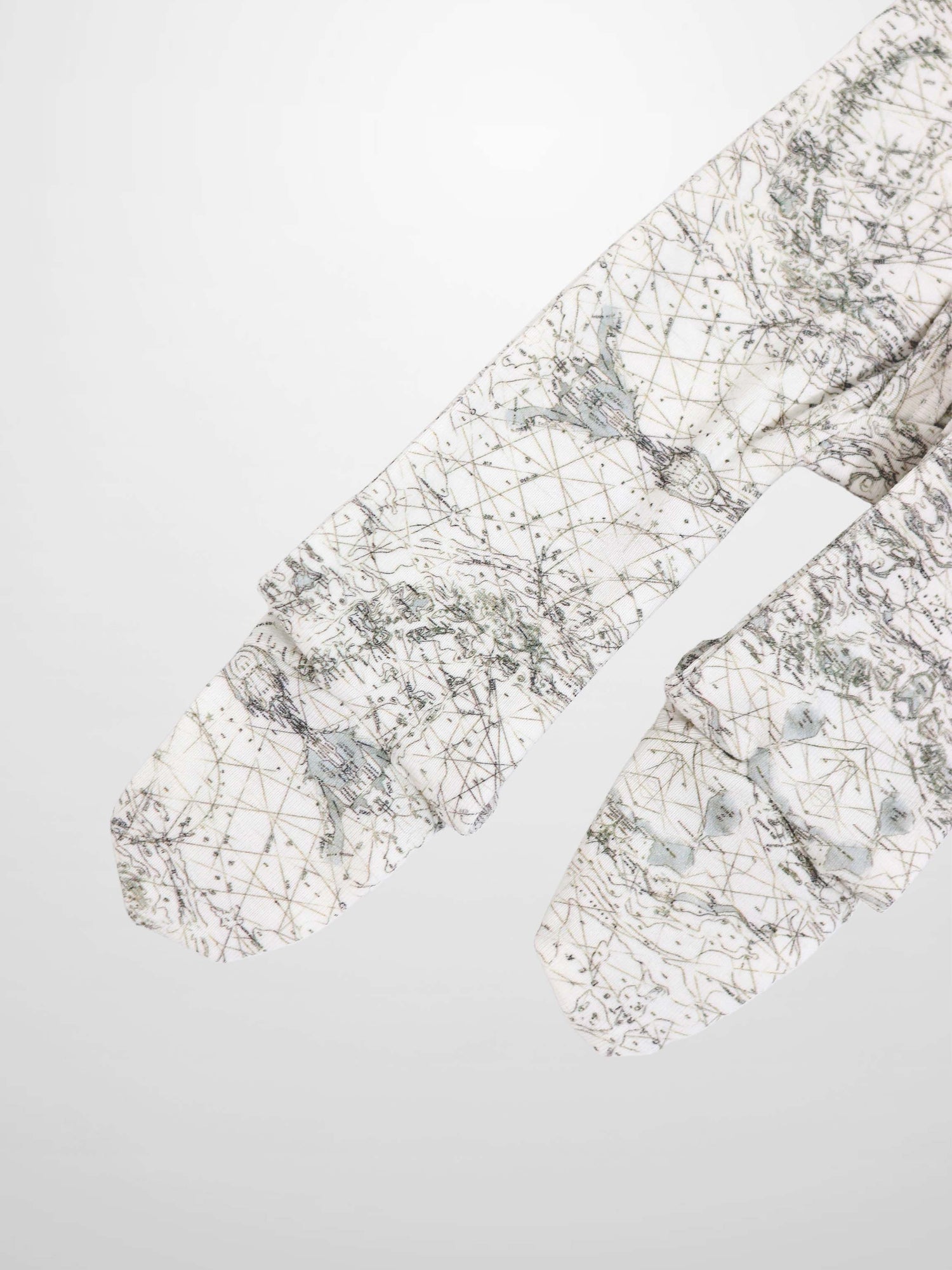 Map Stretchy baby jumpsuit footie fabric in off-white with sage green map lines and compass markers.