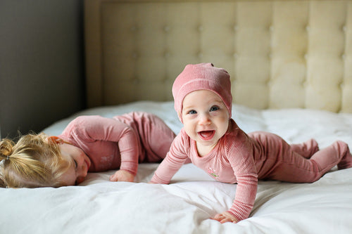 baby girls playing in a bed with a soft beanie hat on her head
