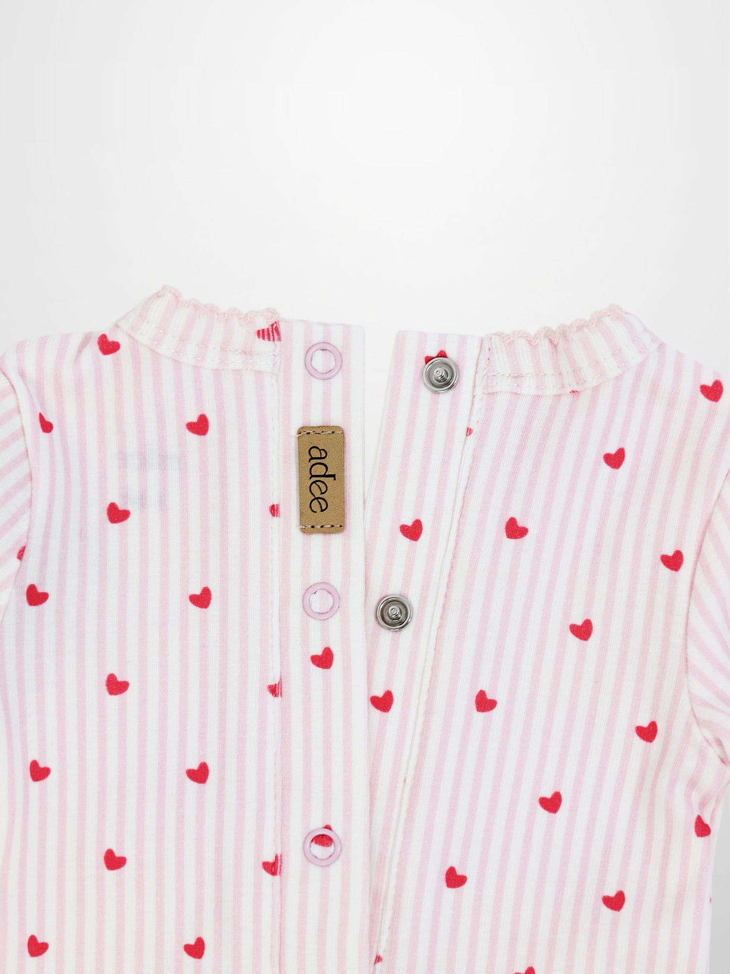 Back view of light pink and white striped baby jumpsuit with red hearts, back snaps, and scalloped trim.