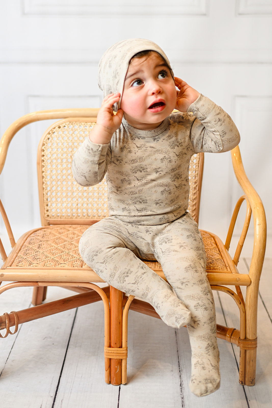 cute and sweet toddler boy wearing a jumpsuit footie with a beanie hat happy and content