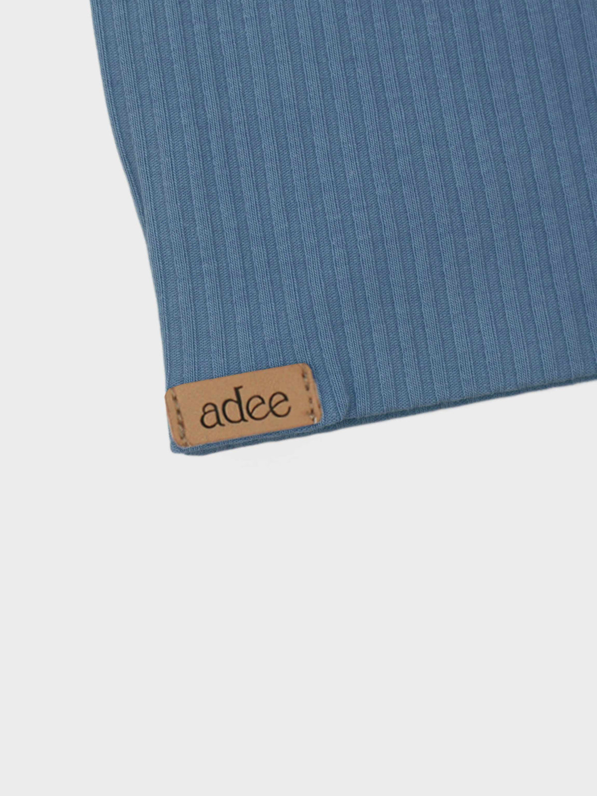 Blue thin-ribbed baby beanie with tan leather patch and adee branding