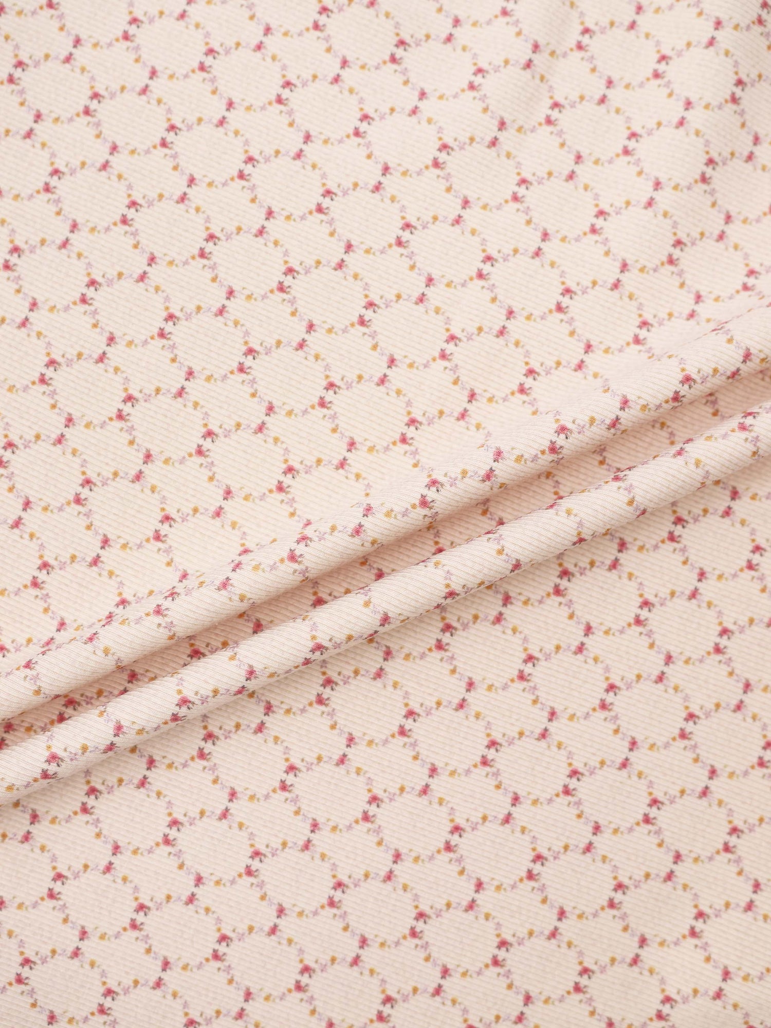 Floral Garland Layette Set fabric by Adee, peach background with tiny pink and yellow flowers.