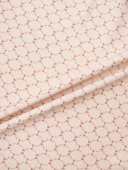 Floral Garland Layette Set fabric by Adee, peach background with tiny pink and yellow flowers.