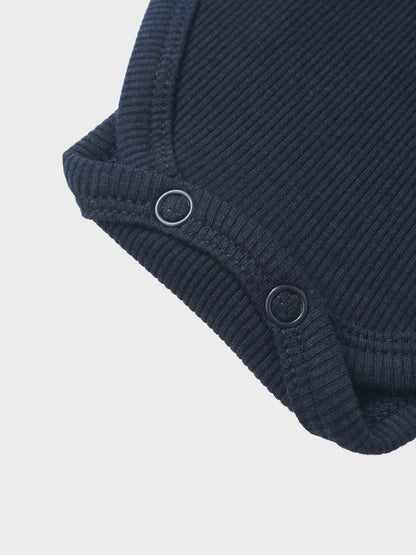 Ribbed mock-neck bodysuit by Adee in navy; unisex dressy top with ribbed knit texture and metal ring accents.