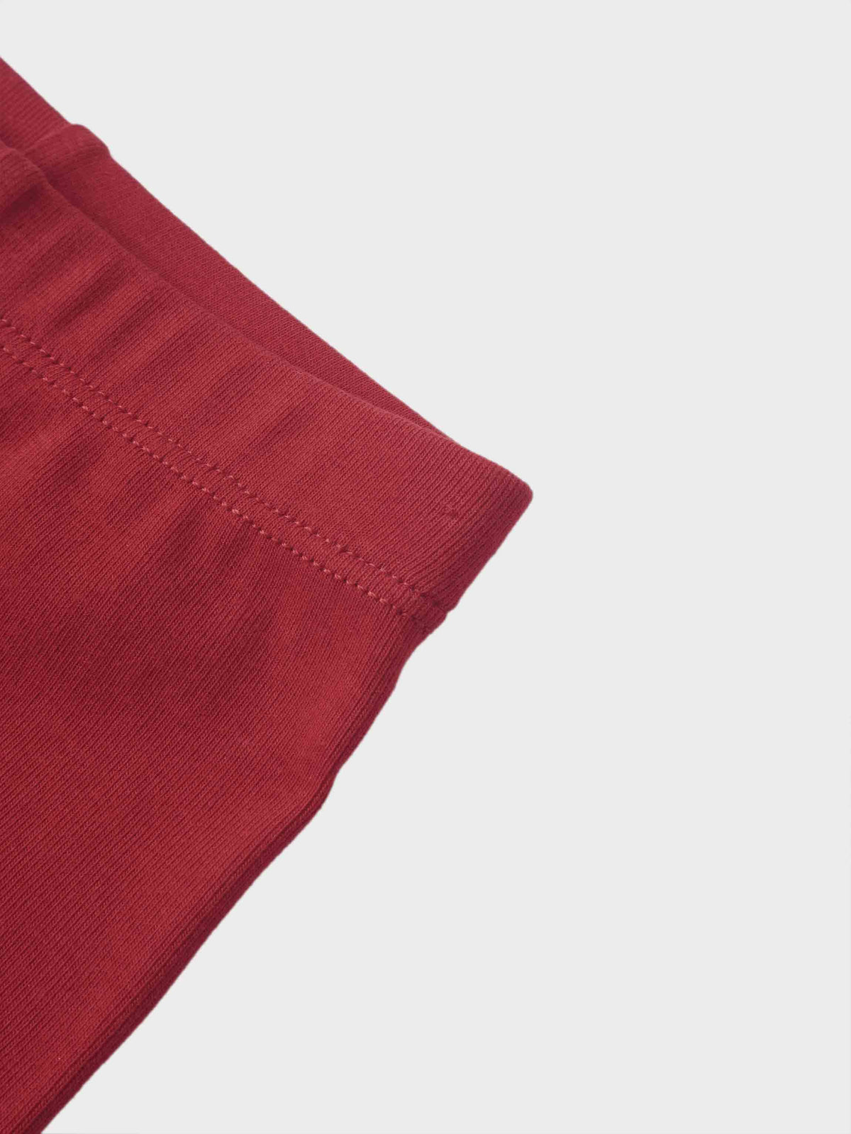 Non ribbed leggings in red, close-up of the cuff with stitched hem.