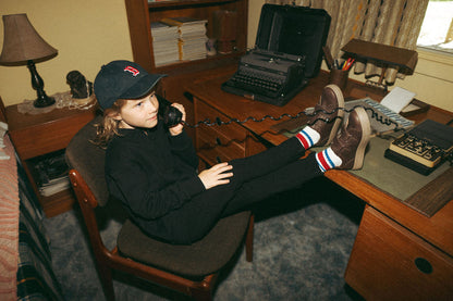Stretch pants - black; child wearing black pants with striped socks and brown sneakers, feet resting on a desk.