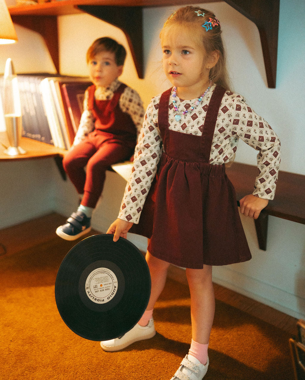 Denim jumper burgundy girls dress by Adee; worn over a patterned long-sleeve top.