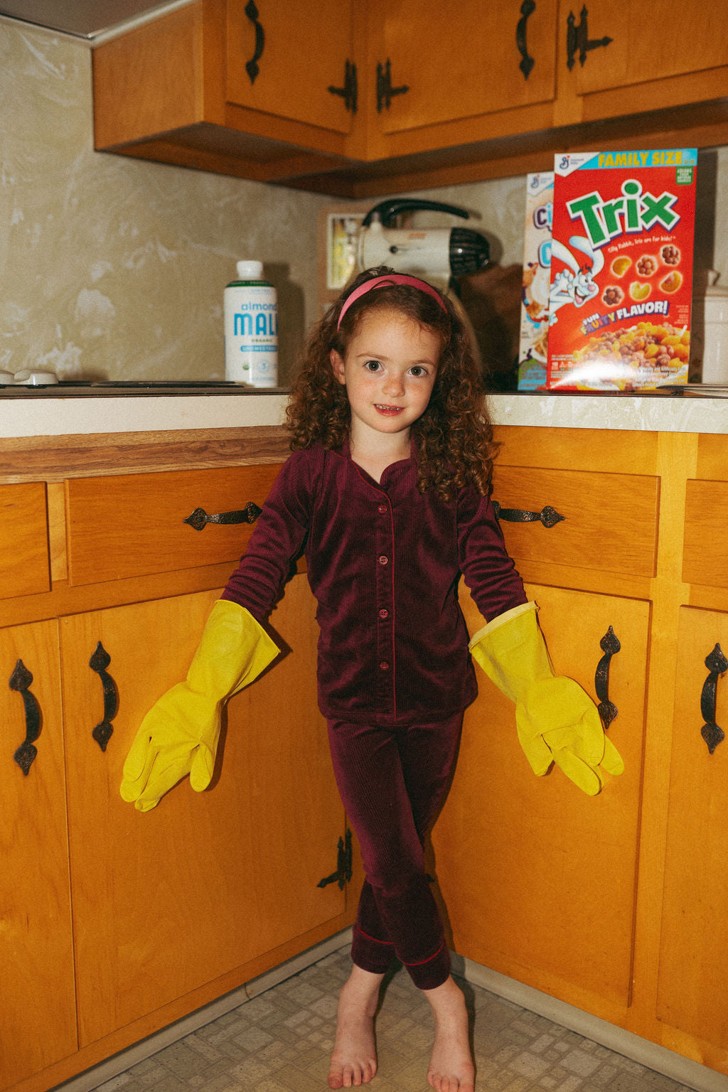 Girls burgundy ribbed velour pajamas worn by a young girl in a kitchen