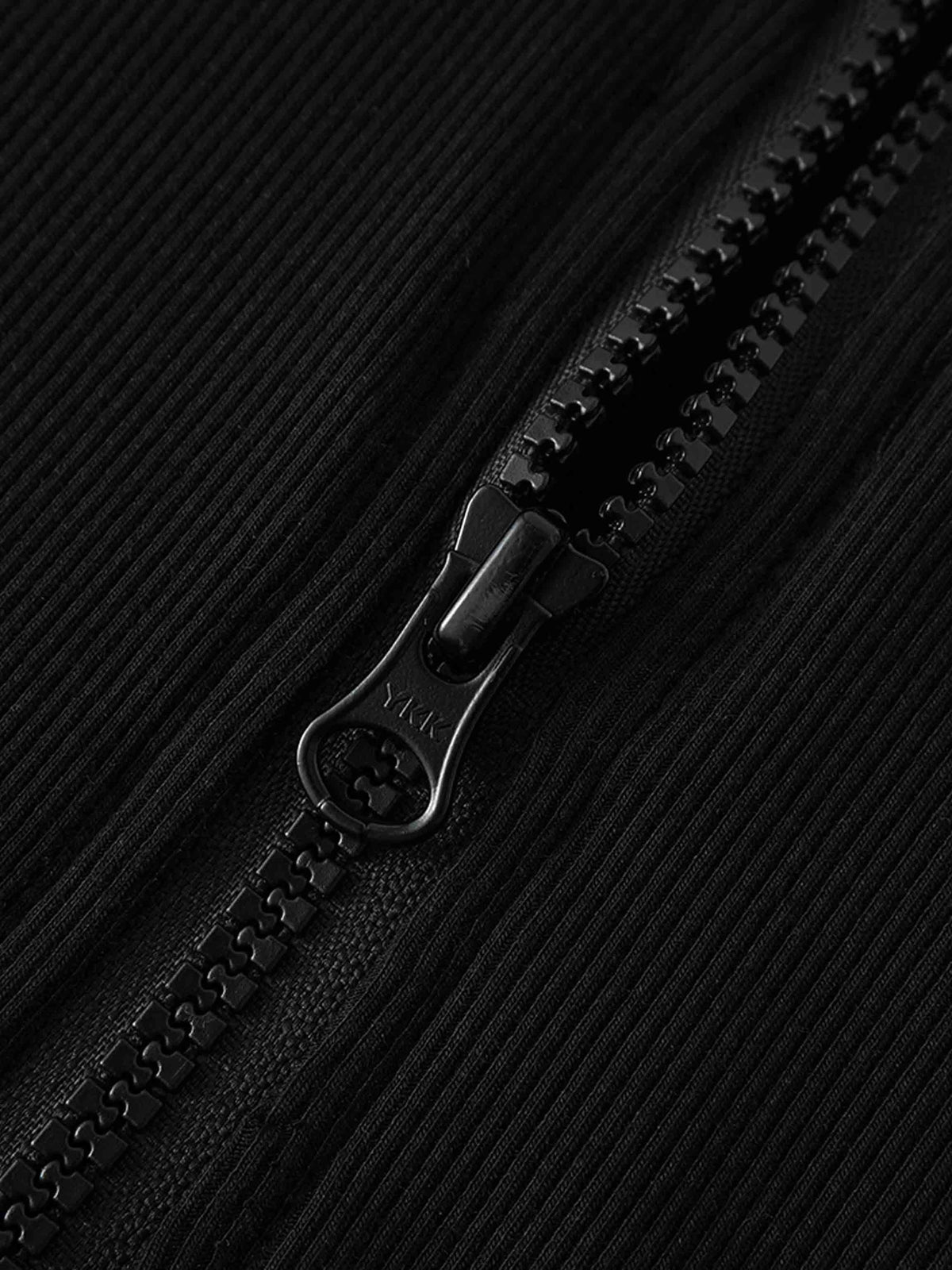 Close-up of black ribbed zip sweatshirt front zipper on thin, lightweight fabric