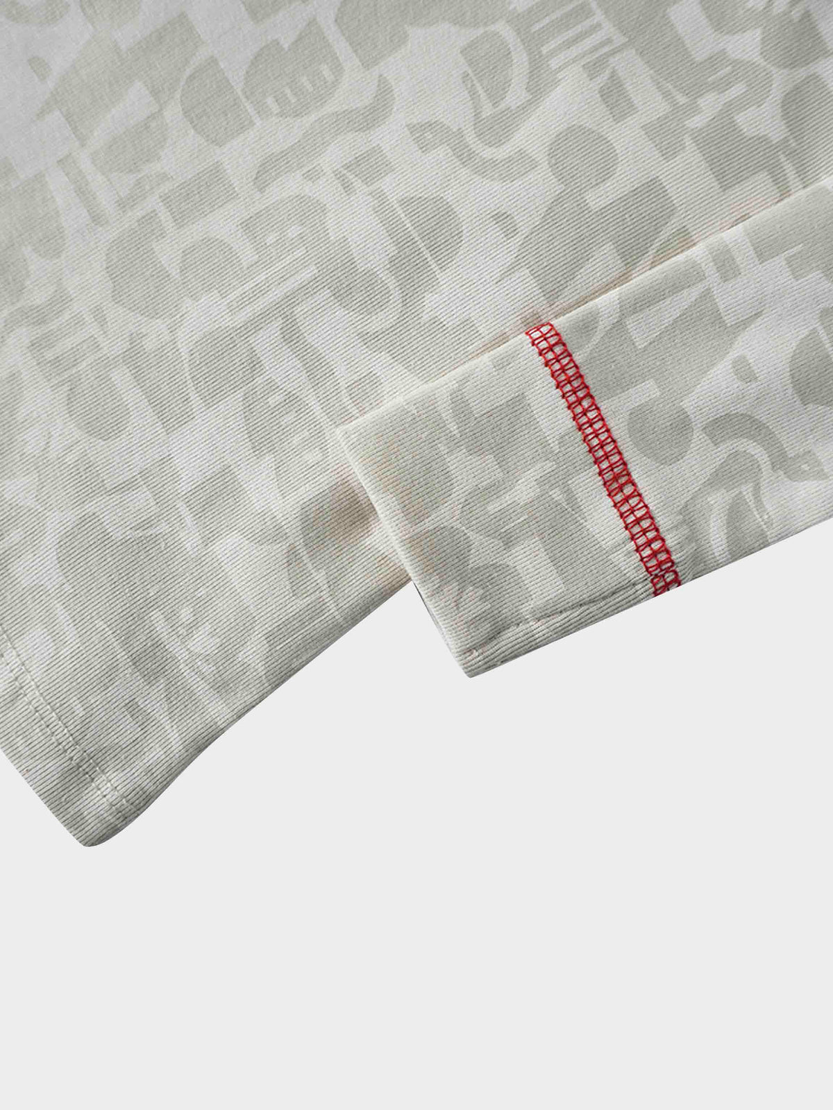 Close-up of Abstract Pajamas-Red fabric with bold red contrast stitch on a neutral patterned sleeve cuff.