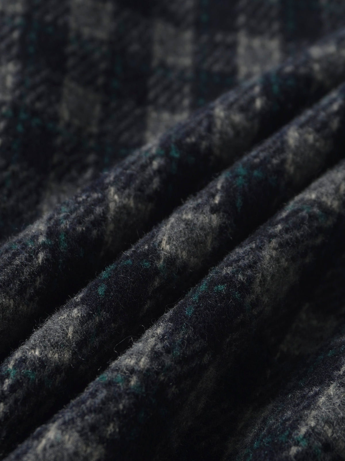 Plaid navy pants fabric close-up with green accents and wool-like texture