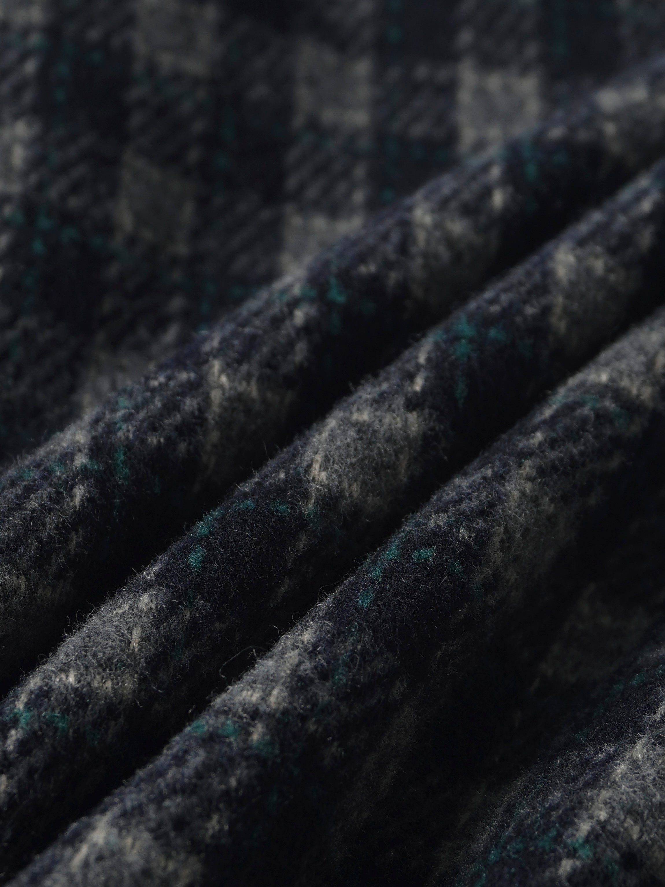 Plaid navy pants fabric close-up with green accents and wool-like texture