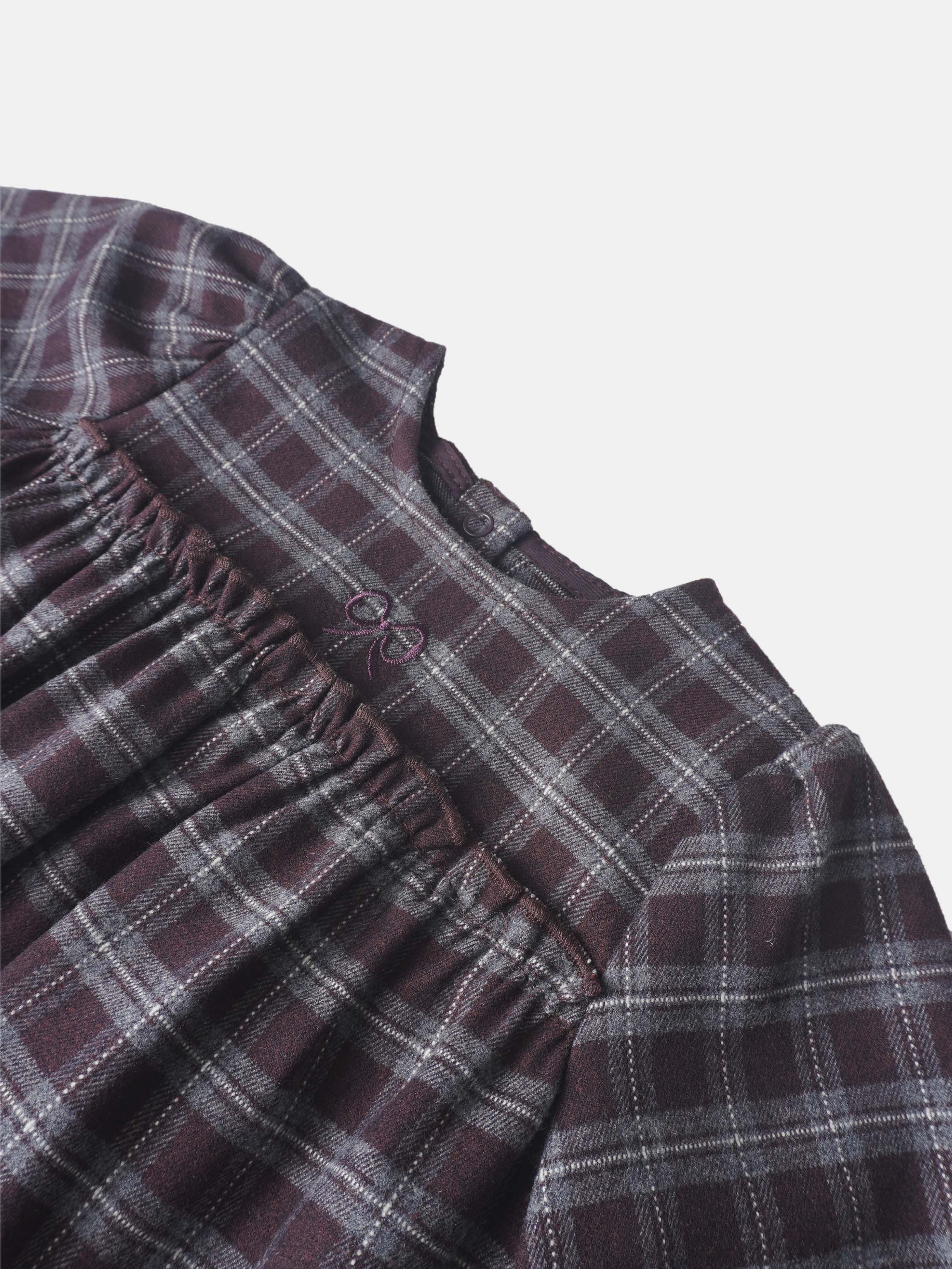 Girls burgundy plaid romper close-up showing elastic waist and buttoned neckline