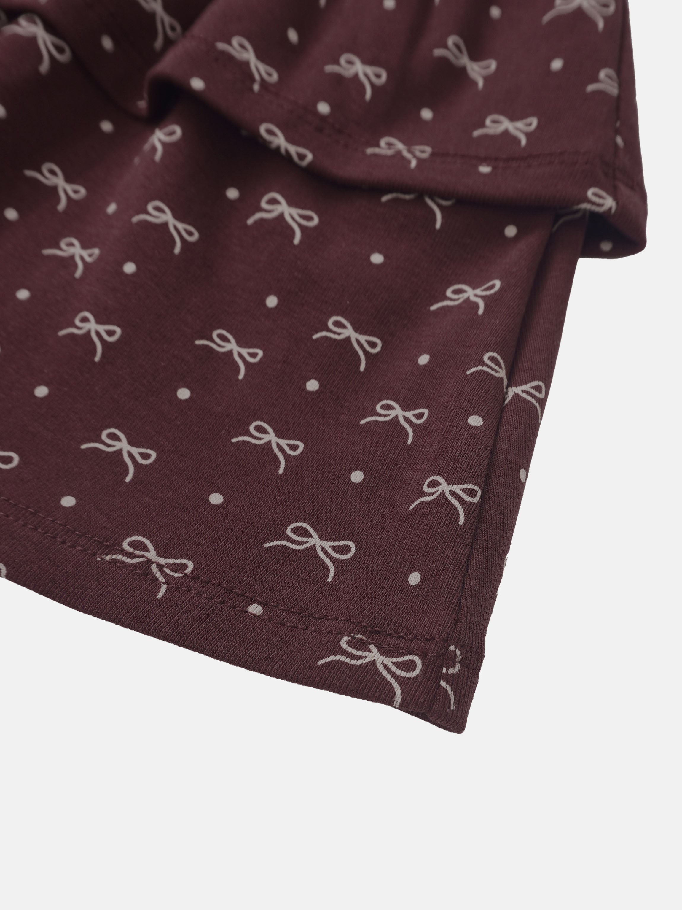 Burgundy bow-patterned girls skirt fabric close-up showing white bows and dots