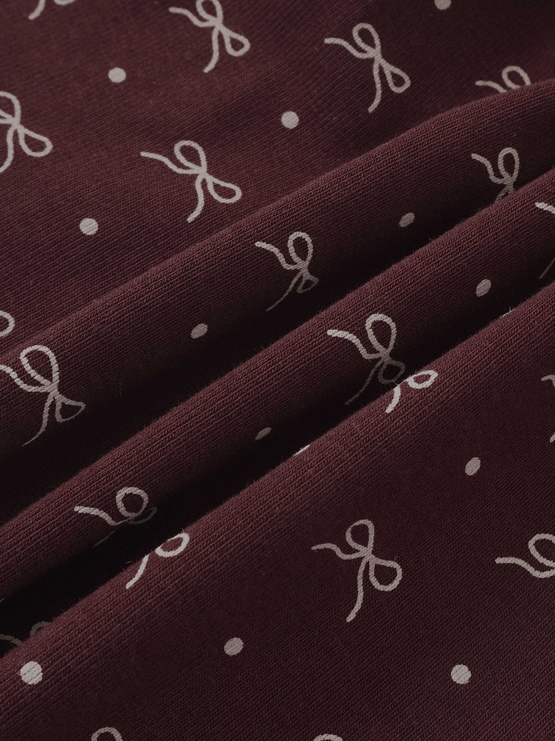 Burgundy Bow Layered Skirt by Adee; close-up of knit fabric with white bow prints and dots.