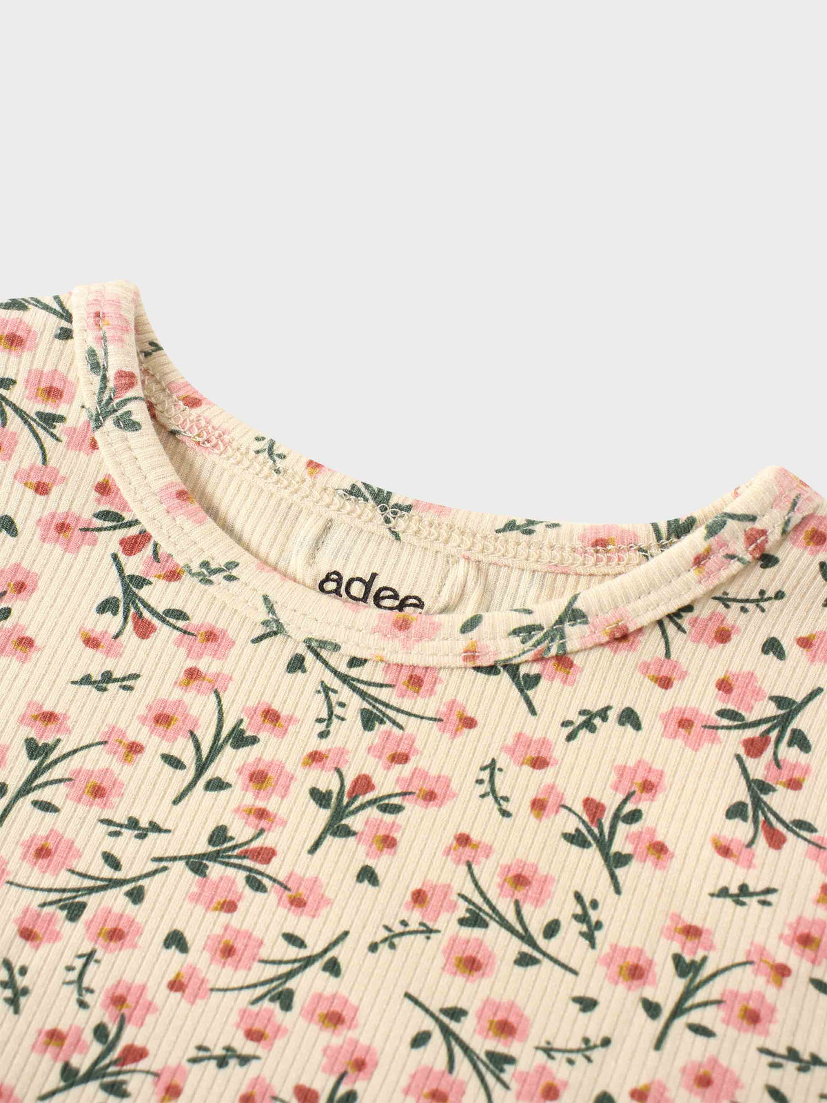 Cream floral-print knit top with pink blossoms and green leaves, close-up neckline.