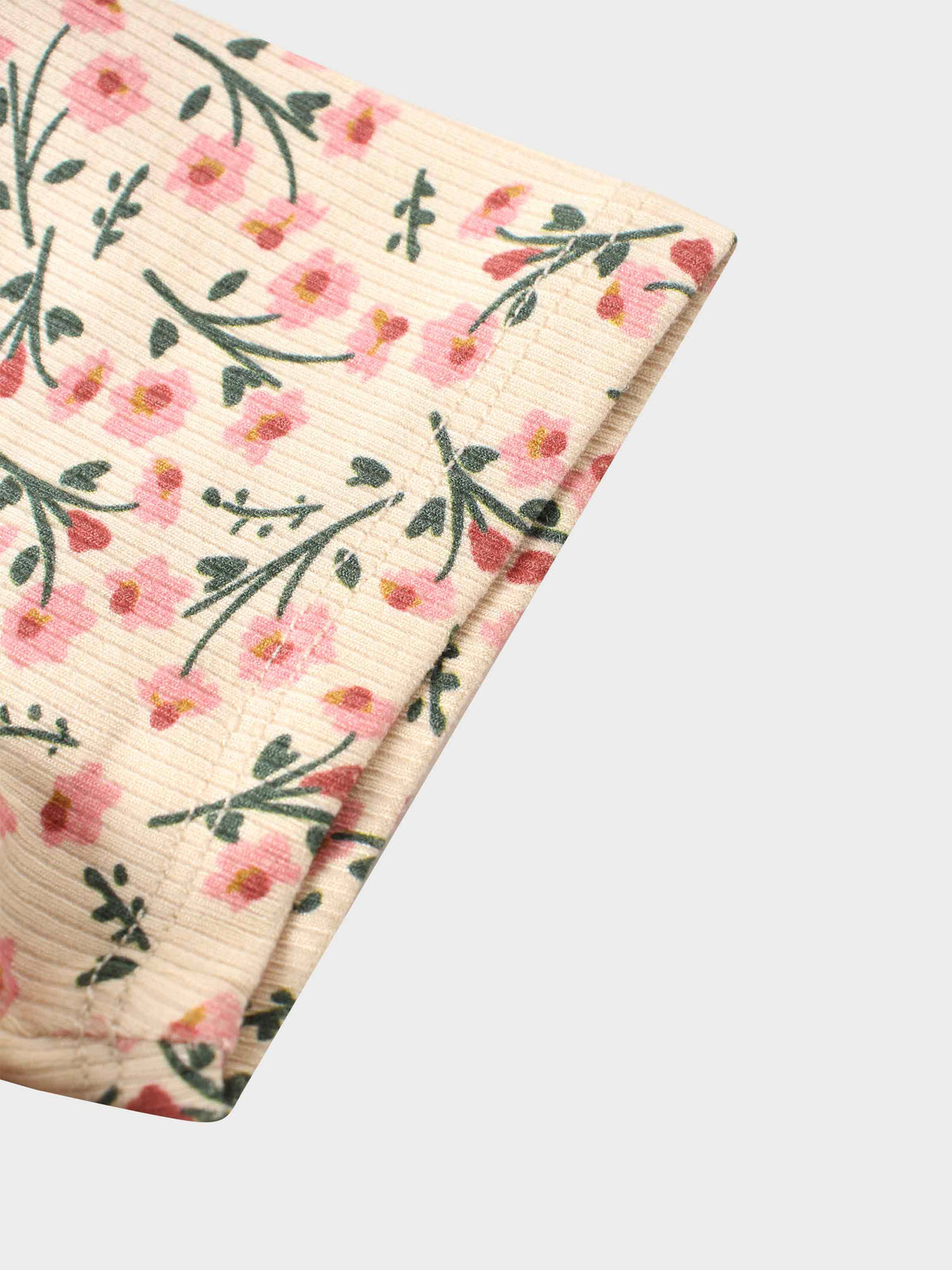 Cream textured fabric with pink flowers and green leaves in a floral print.