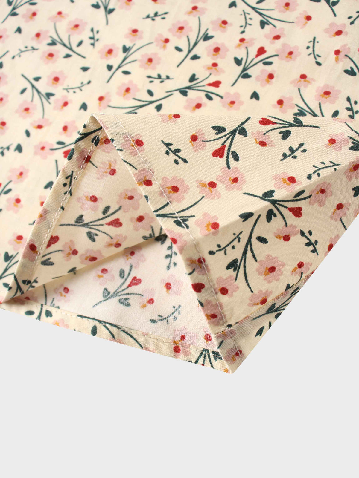 Light tan fabric with pink blossoms and green stems in a floral print; close-up folded edge.