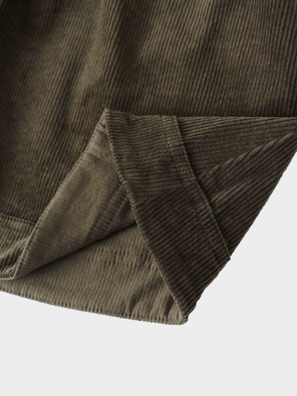 Corduroy skirt in forest green fabric close-up, textured with stitched hem.