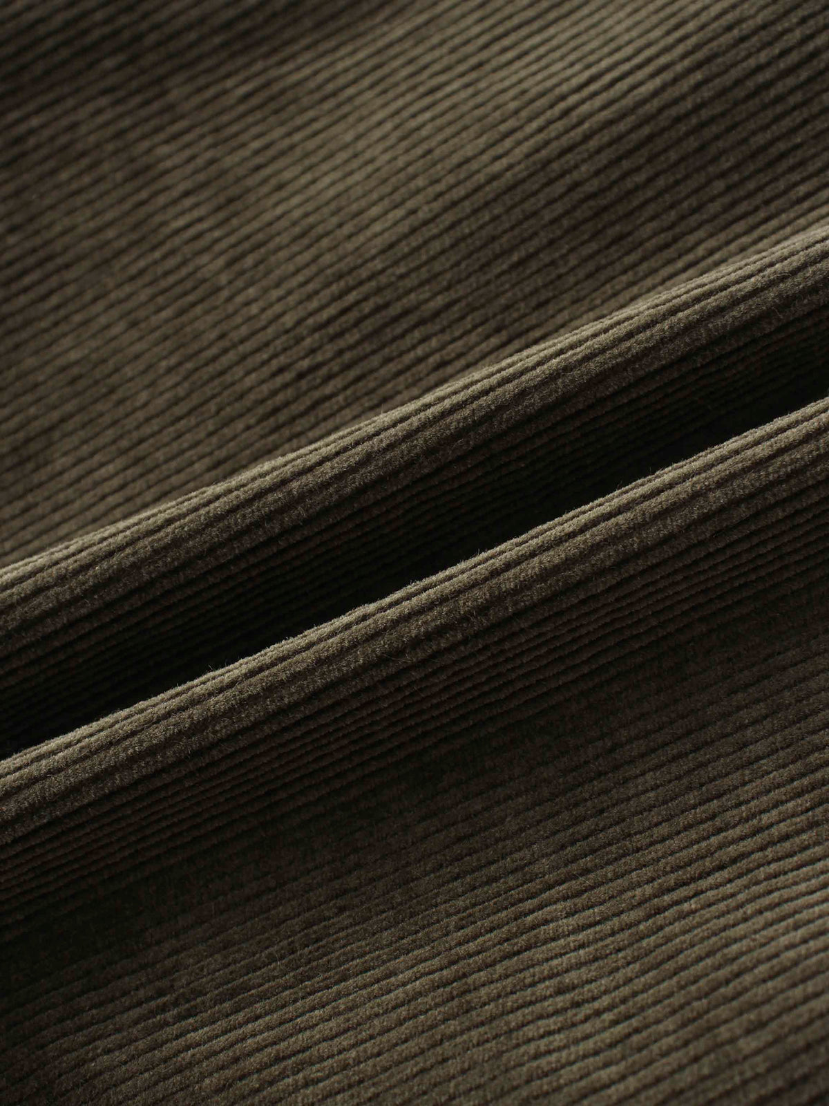 Forest green corduroy fabric close-up with ribbed texture and soft, cozy feel.