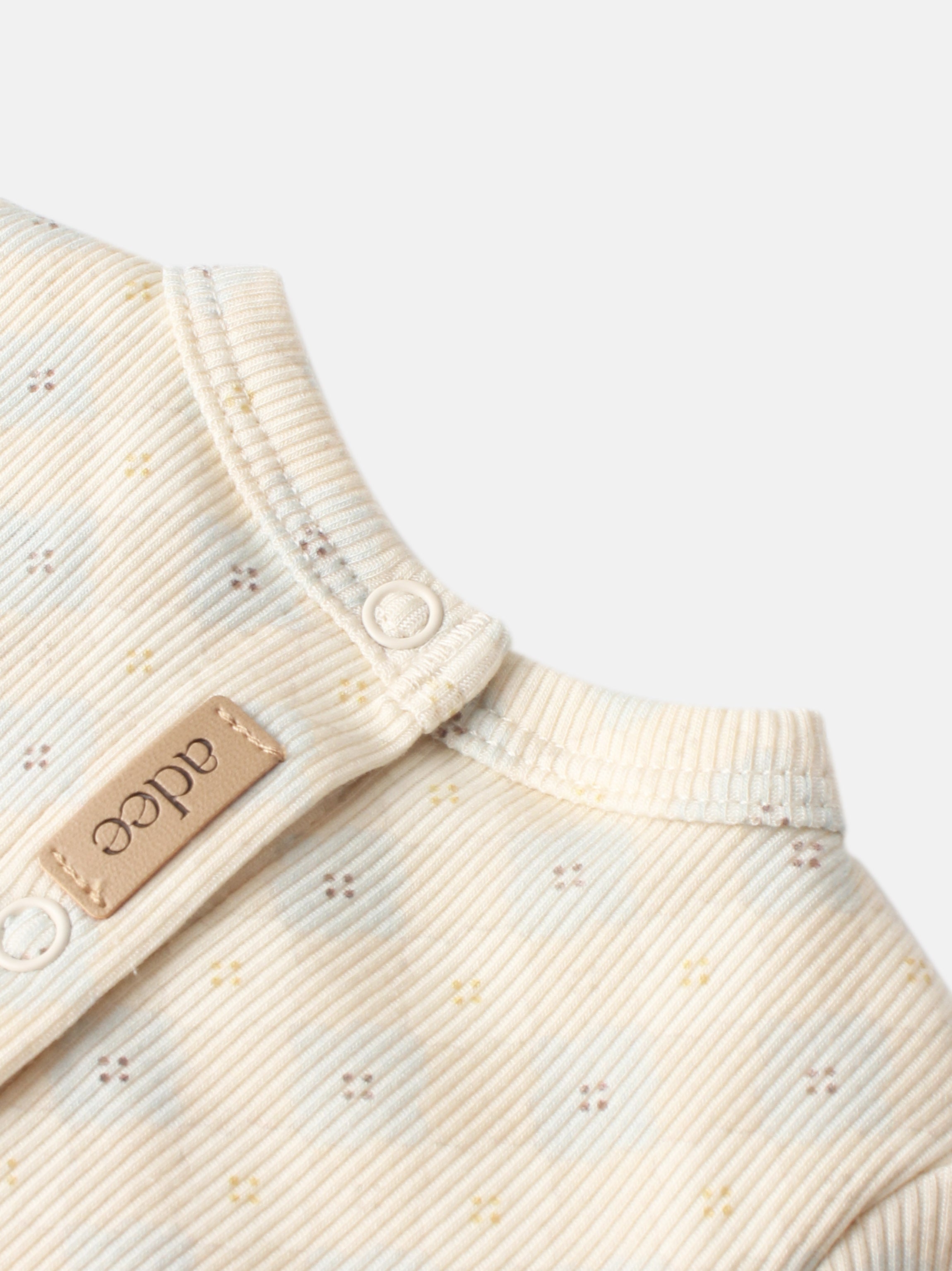 Little Button Stretchy - Blue by Adee; cream ribbed fabric with a small dotted pattern and a white snap.