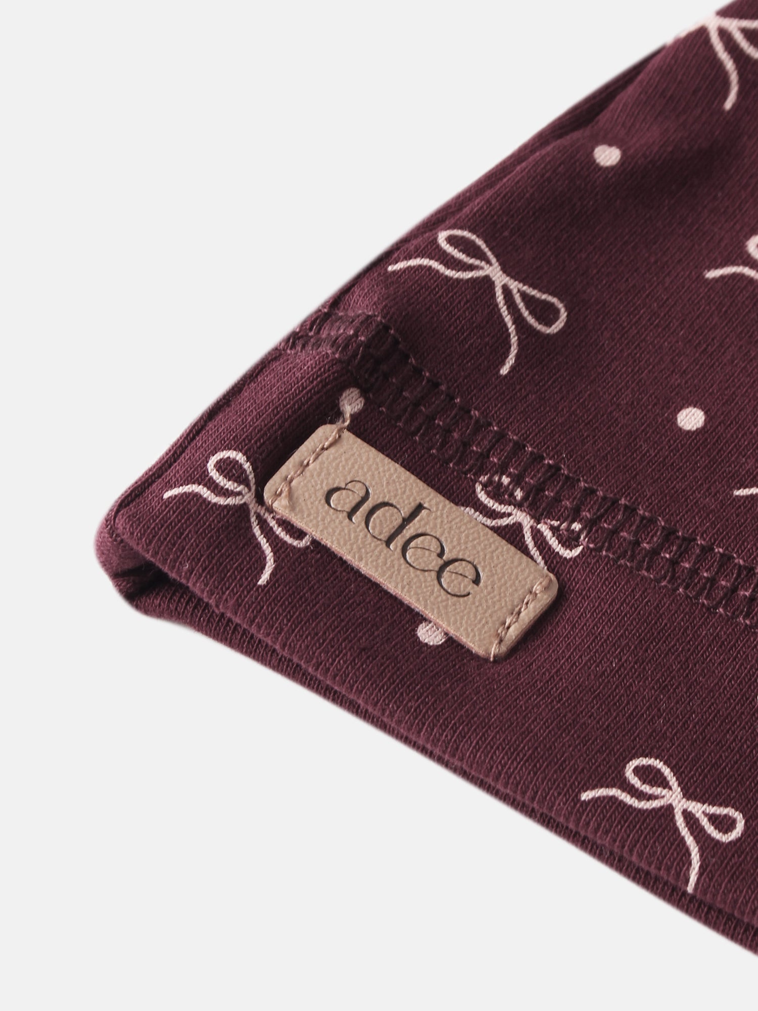Girls burgundy bow hat by Adee with white bow print and beige label