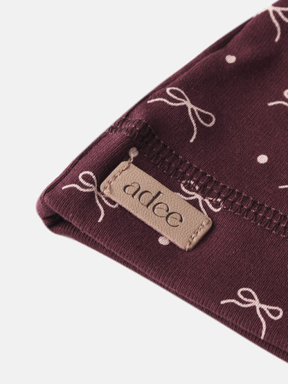 Girls burgundy bow hat by Adee with white bow print and beige label