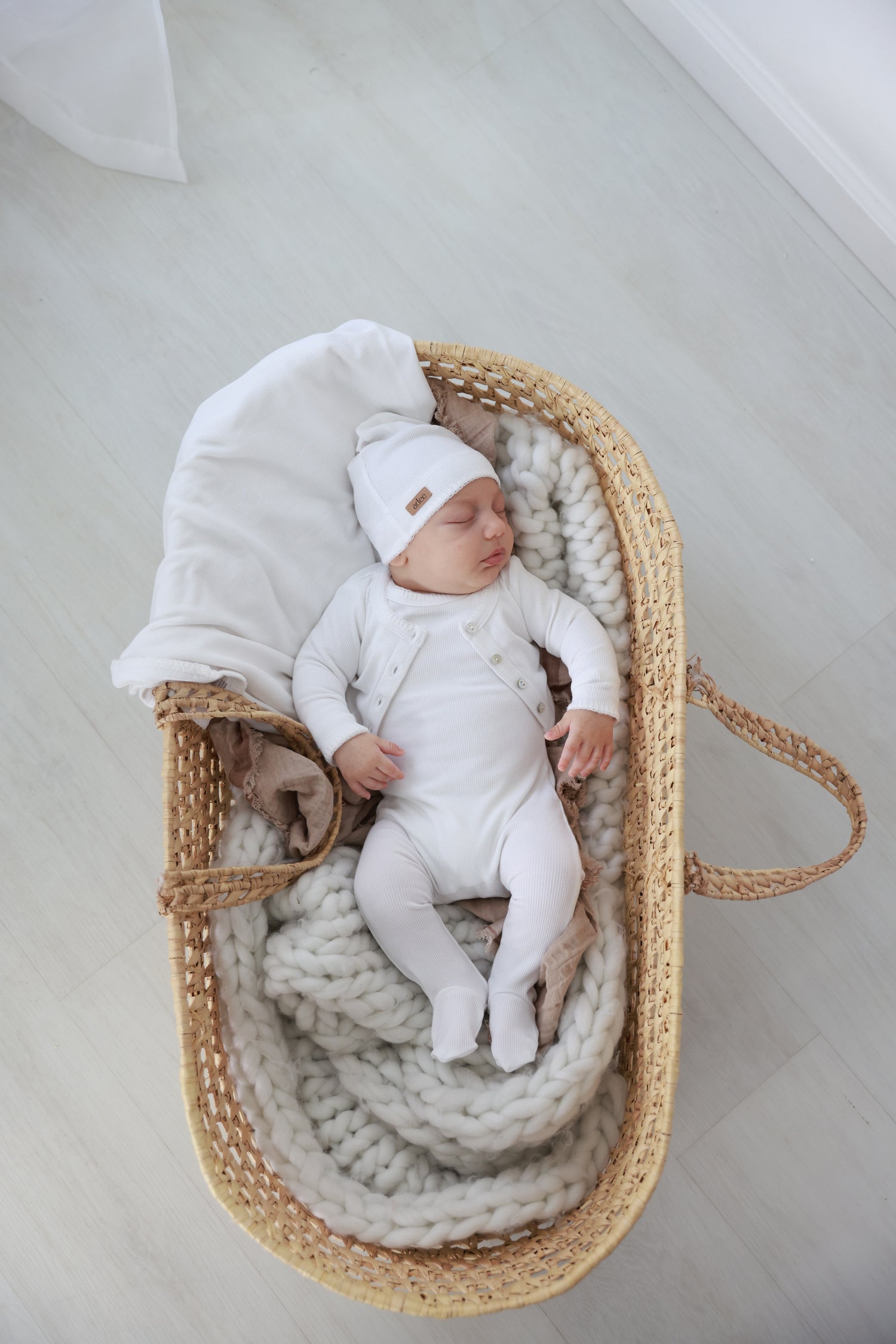 Legacy Stitch Stretchy White unisex baby outfit by Adee in a woven basket.