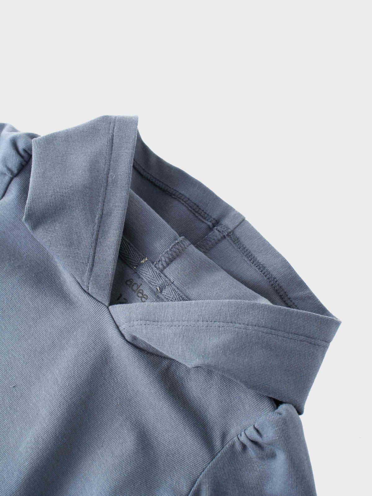 Blue cotton hoodie close-up showing collar and hood seam.