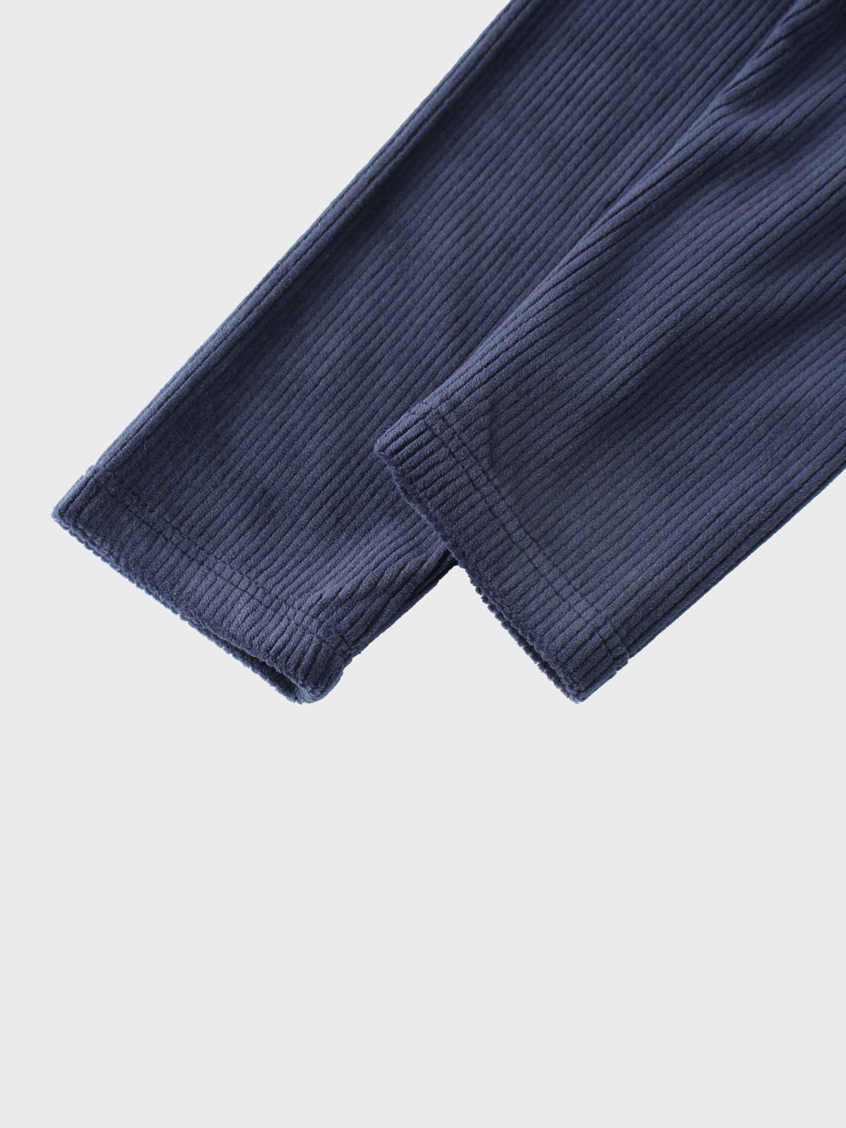 Close-up of navy ribbed velour pajama fabric with cuffed sleeve.