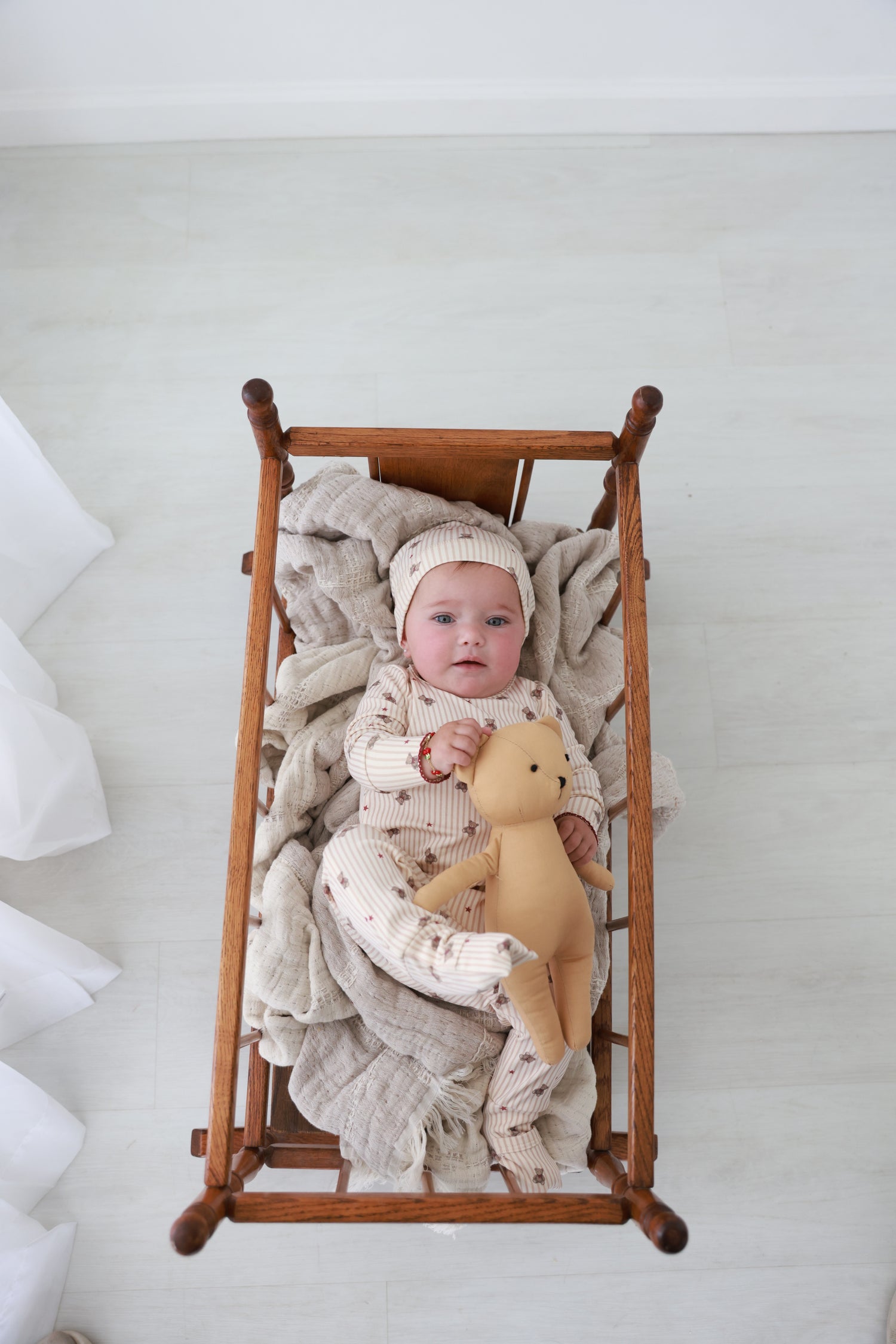 Striped Bear Stretchy - Red, Adee girls stretchies; baby sits in wooden rocking chair with a plush bear.