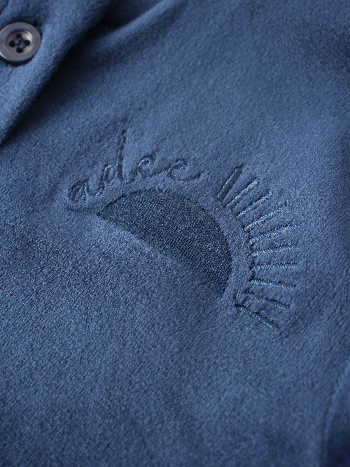 Close-up of navy velour fabric from Velour Bomber Set, featuring embroidered curved design on chest.