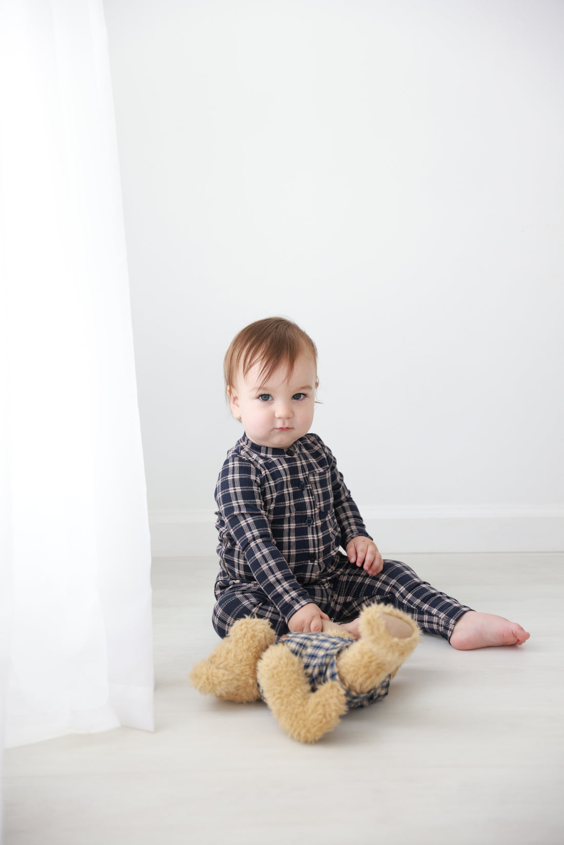 Plaid blue boys pajamas worn by a toddler, cozy cotton sleepwear in a bright home setting.