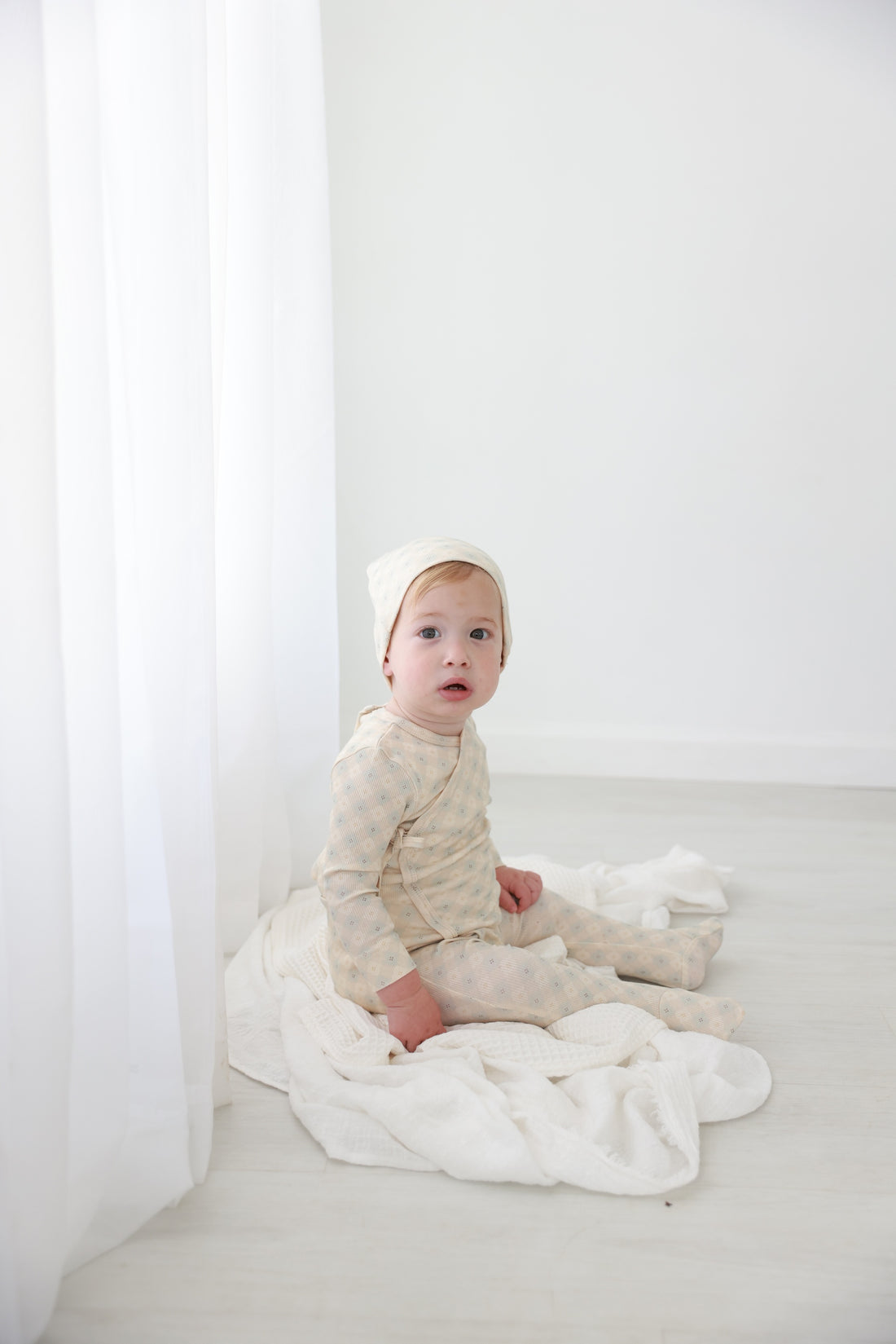 Little Button Blue layette set by Adee; cream-beige baby pajamas on white backdrop.