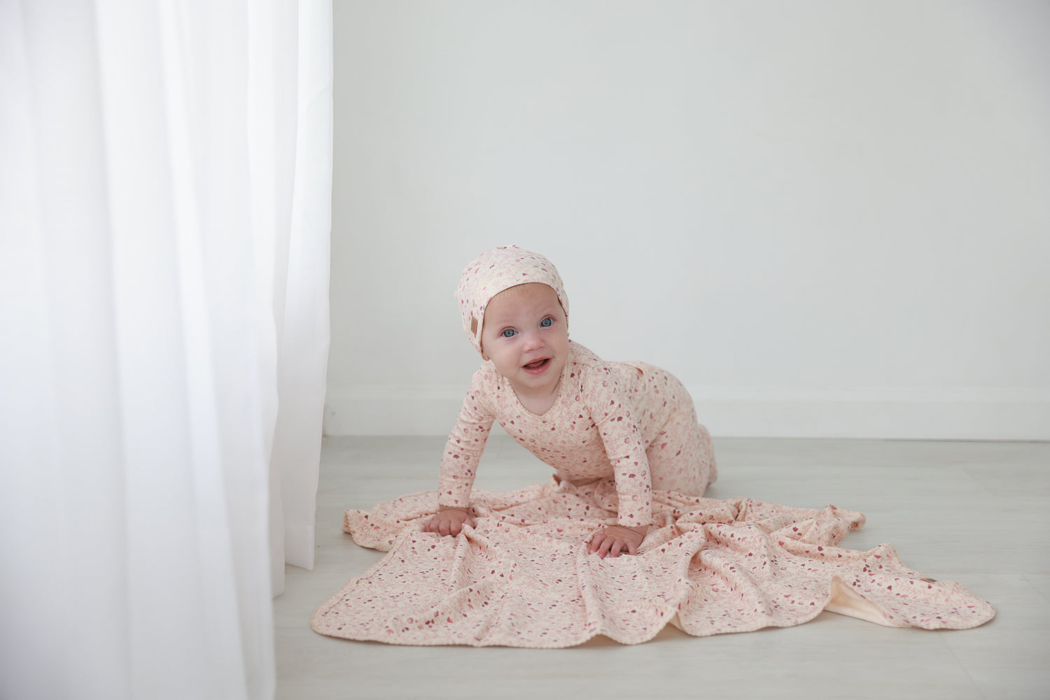 Garden Sprinkles Stretchy girls stretchies by Adee in pink floral print worn by a baby.