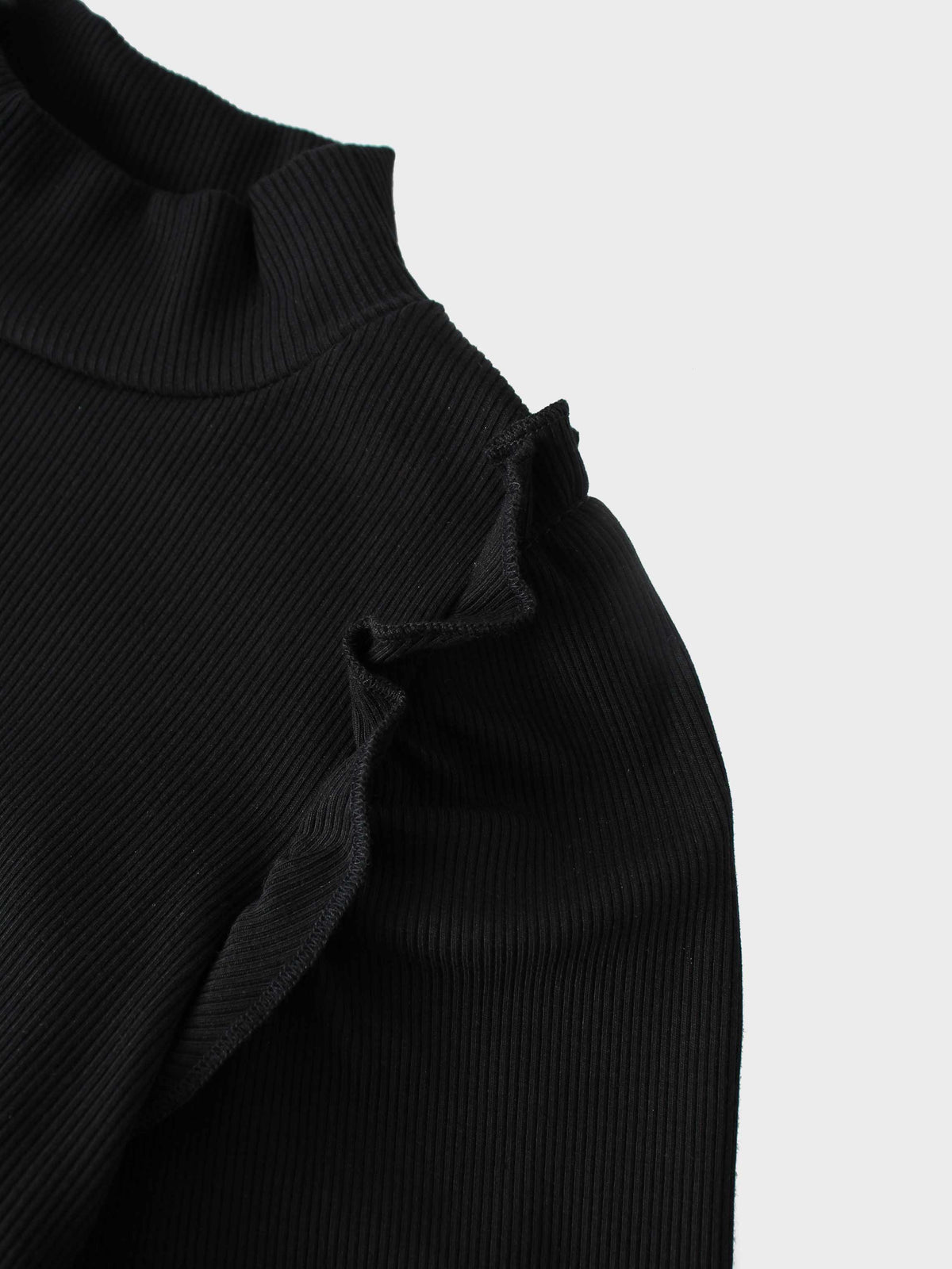Ruffle puff sleeve black ribbed mock-neck shirt; close-up fabric texture.