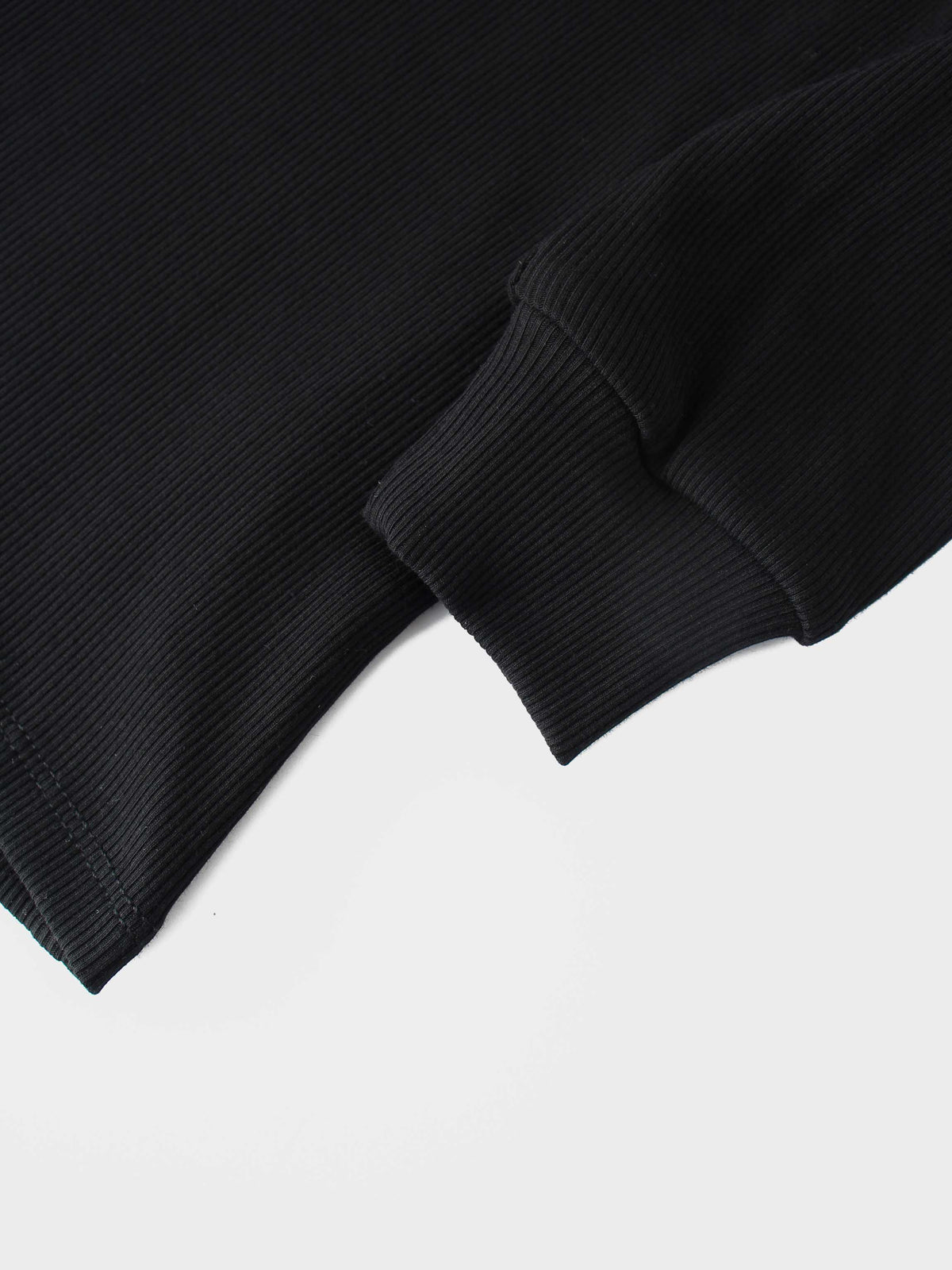 Close-up of black ribbed knit sleeve cuff on a mock-neck shirt.