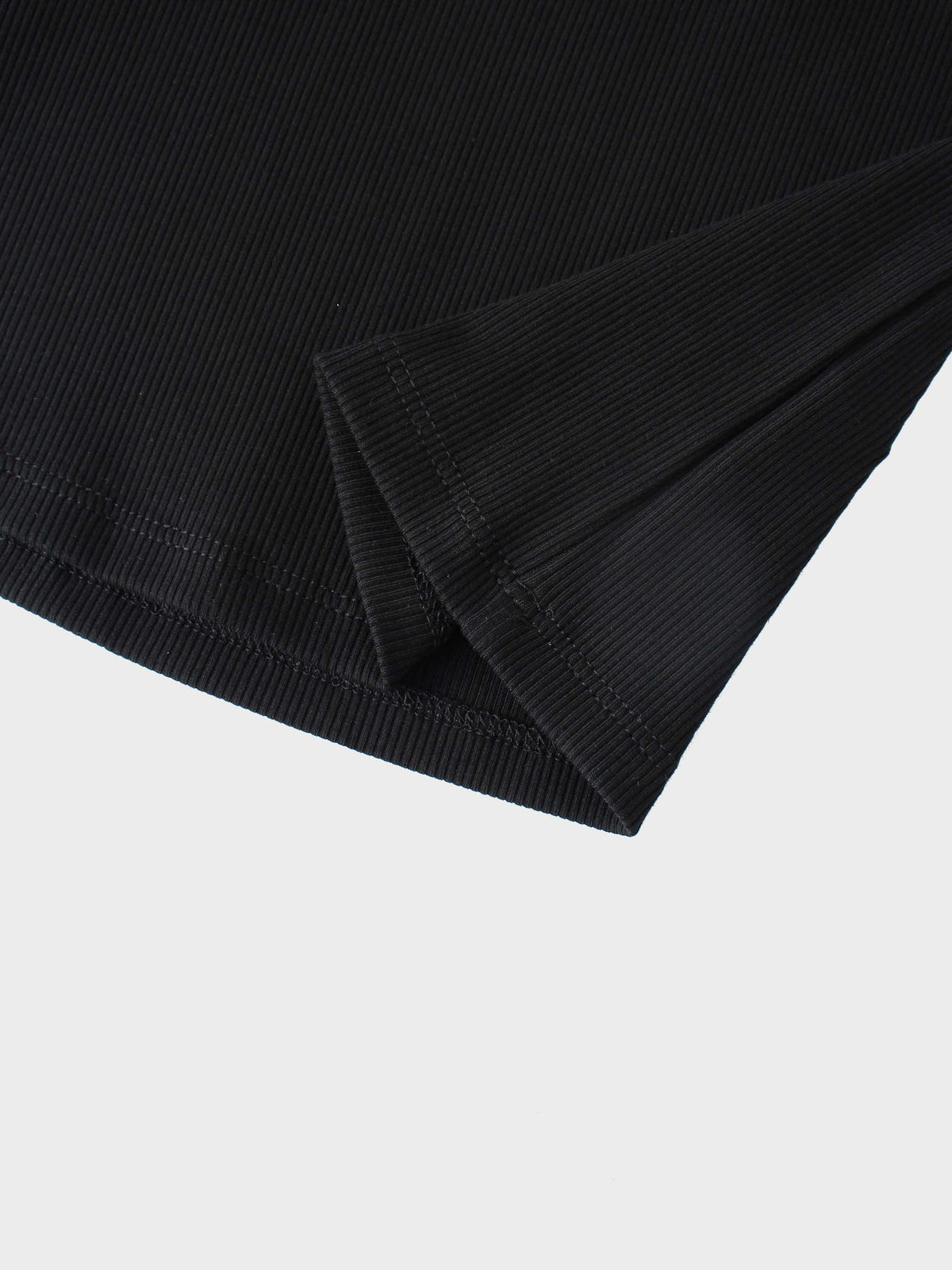 Close-up of black ribbed knit sleeve hem on a mock-neck shirt.