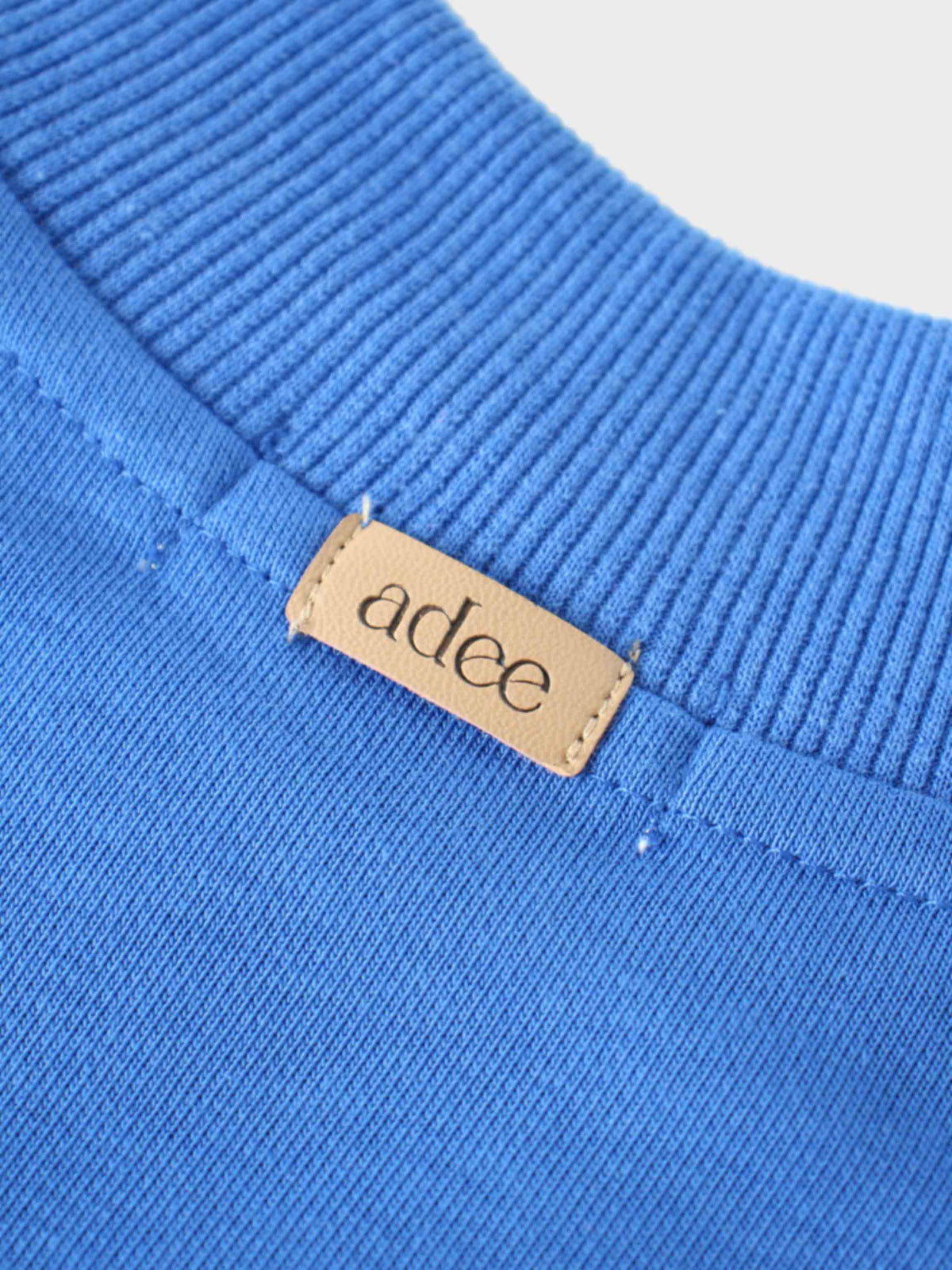 Bike sweatshirt in royal blue, close-up of ribbed neckline and beige stitched label.