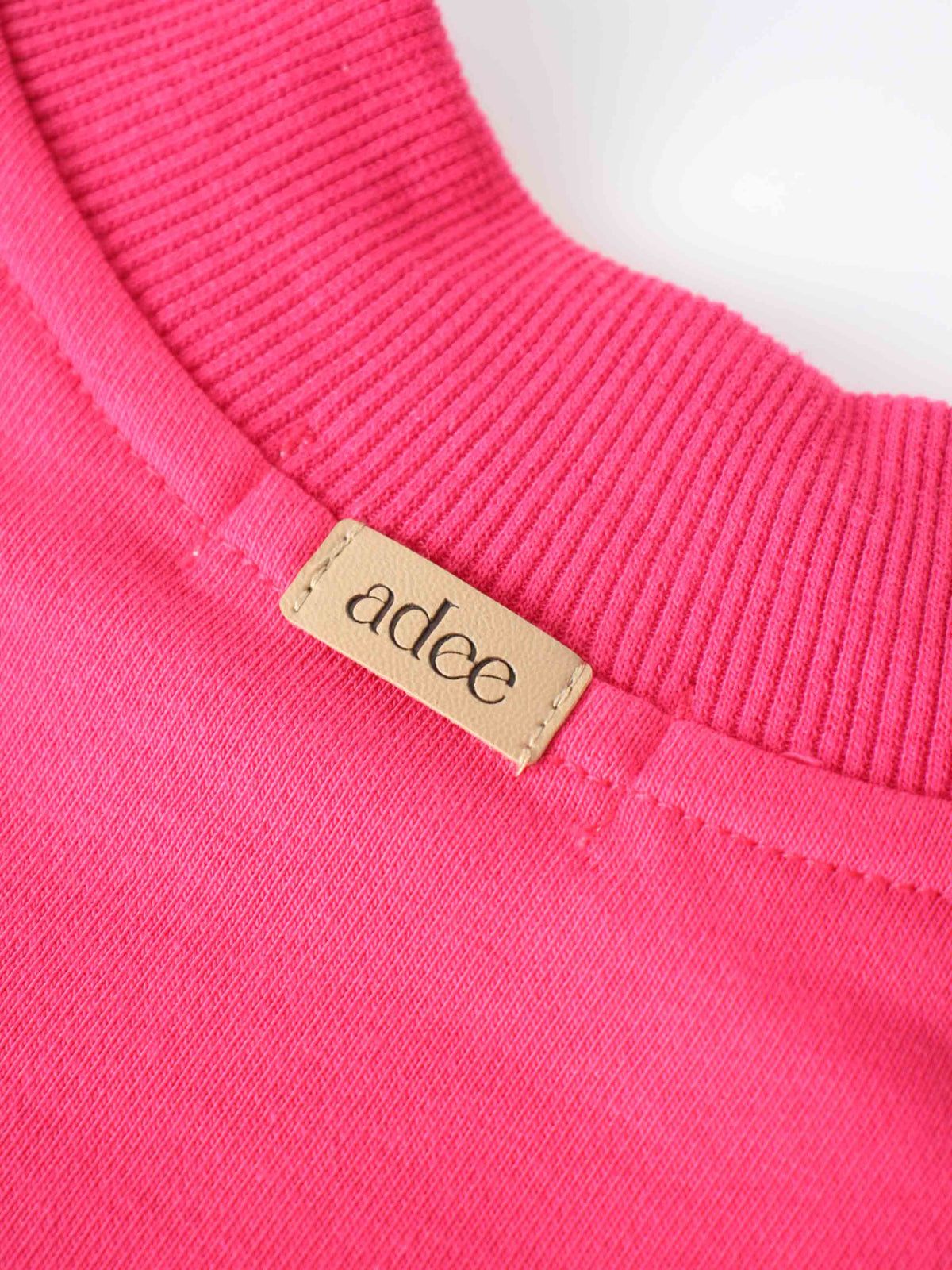 Neon pink bike sweatshirt neckline close-up with beige brand tag &