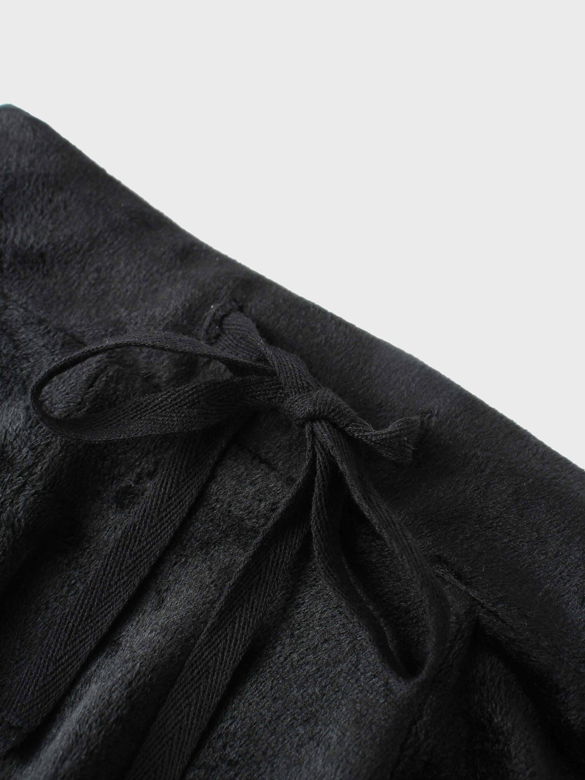 Close-up of black velour six-panel circle skirt with a tied waist bow.