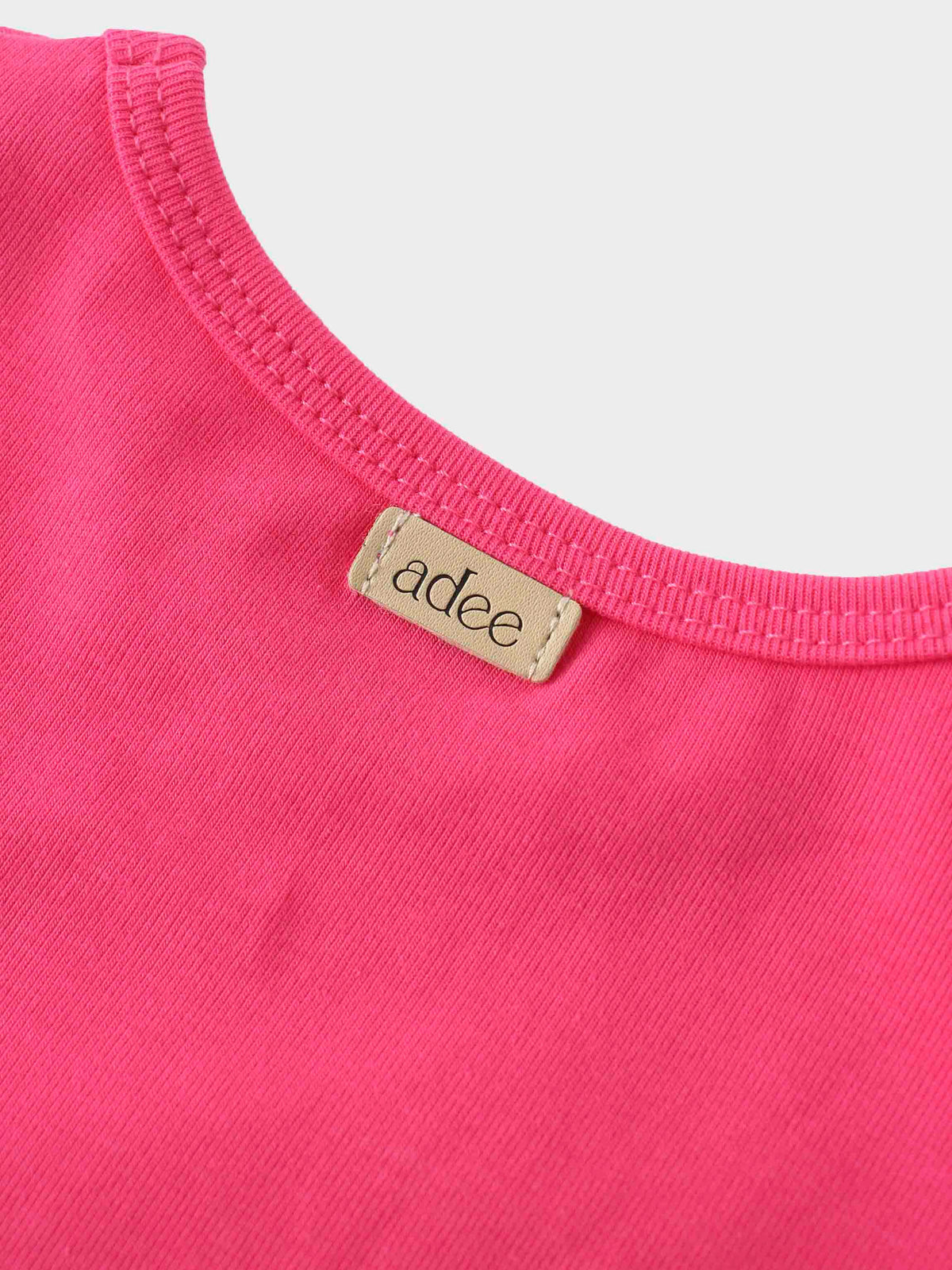 Close-up of pink shirt collar for girls, featuring label.