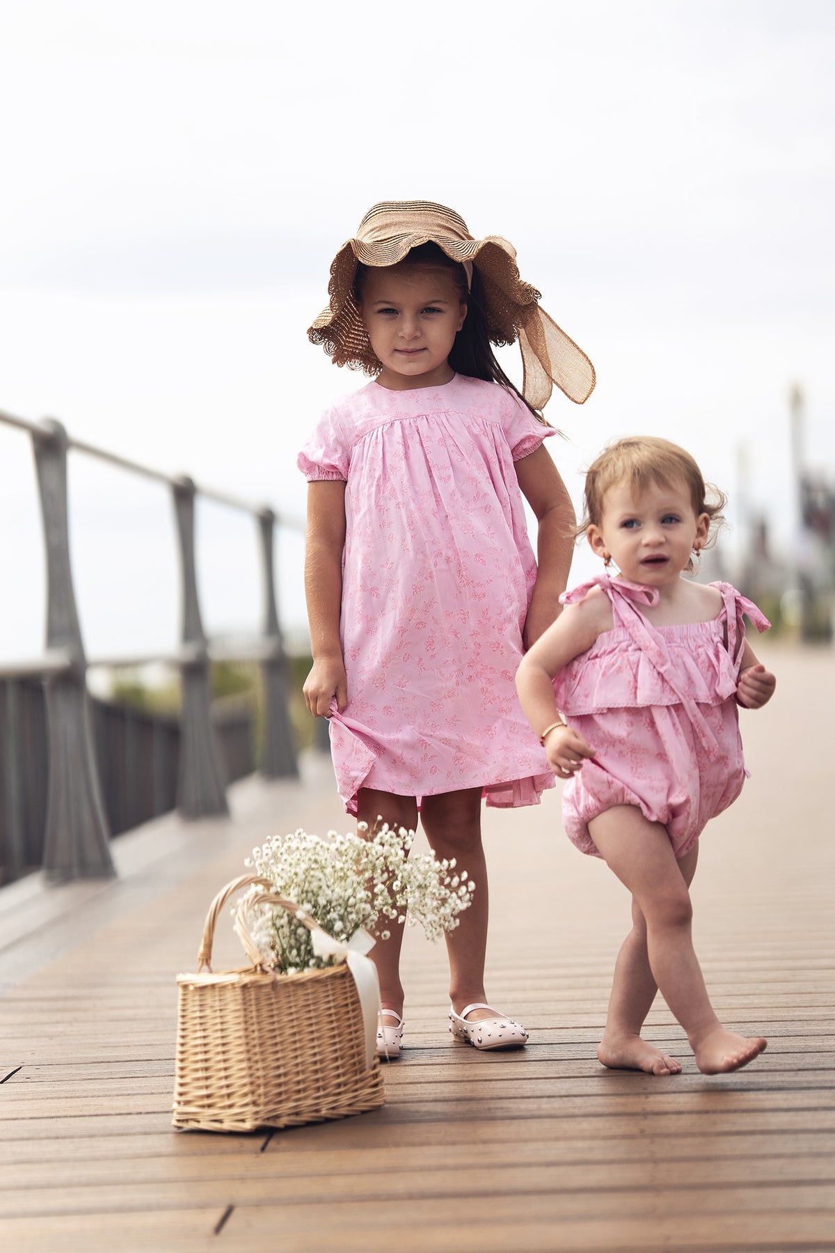 Pink Flower Romper; two pink dressy outfits for girls by Adee on a wooden boardwalk
