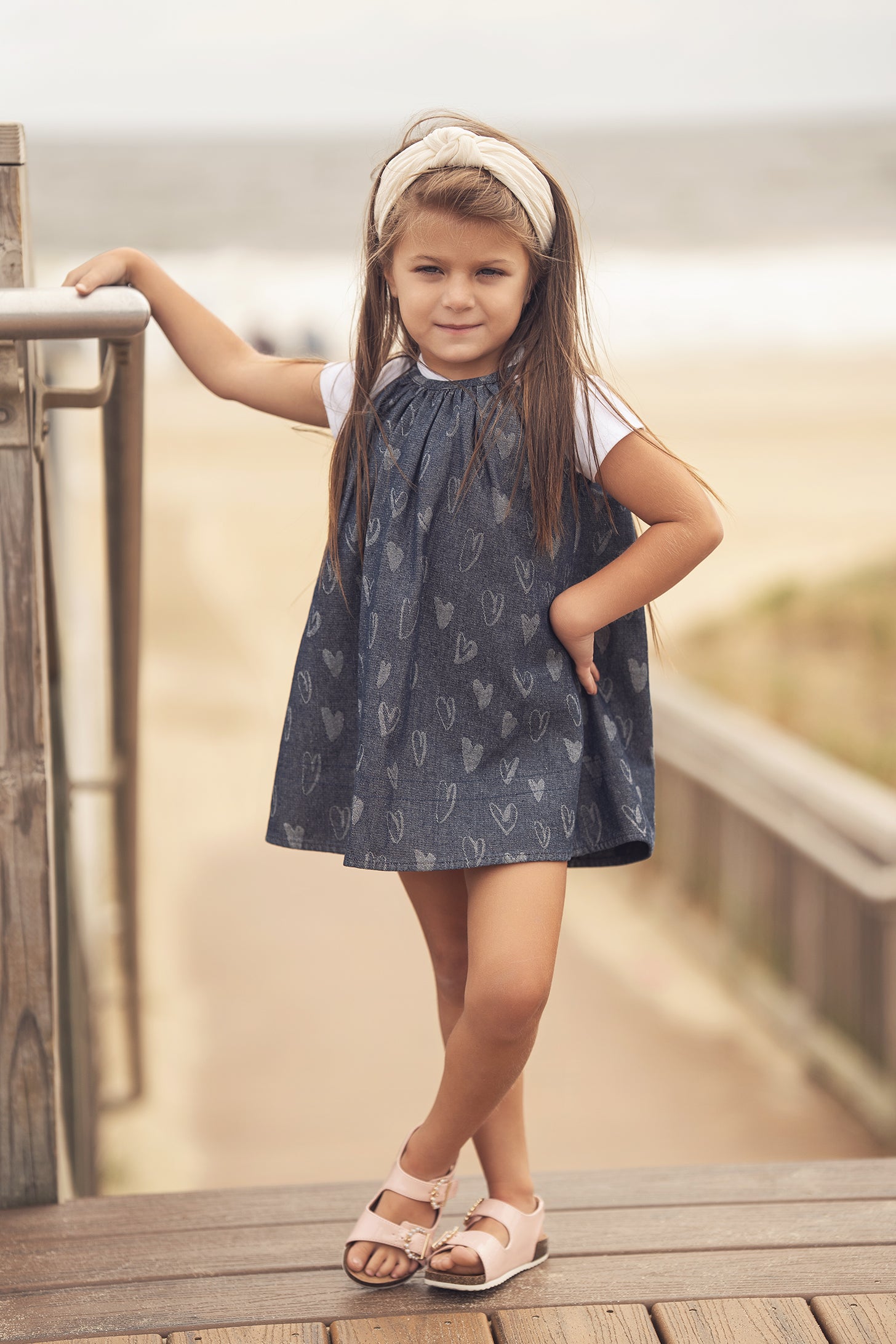 Denim Heart Jumper worn by a girl on a beach boardwalk, white tee sleeves, headband, pink sandals.
