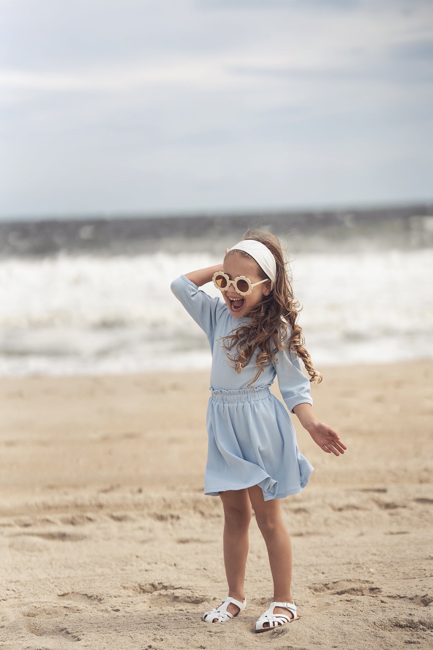 Little girl in light blue 3/4 puff-sleeve dress on the beach.