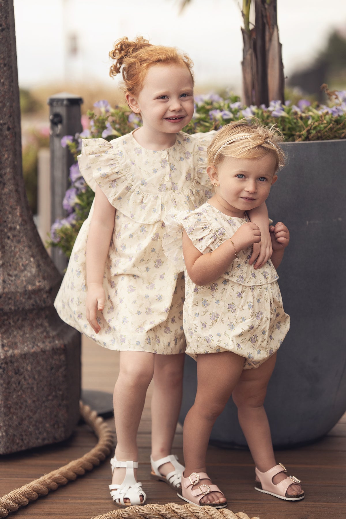 Ivory Flower Romper for girls, dressy floral print, worn by two girls in matching outfits.