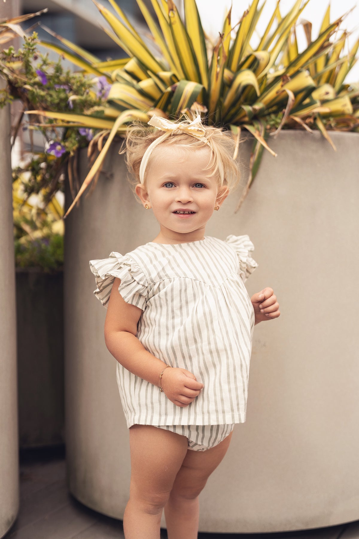 Green striped ruffled shirt and bloomers set by Adee worn by a toddler girl