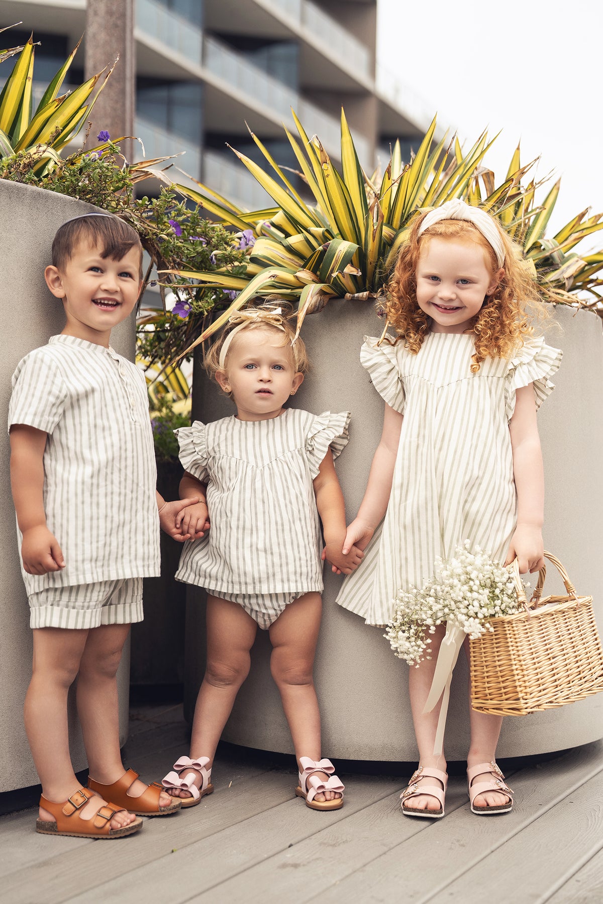 Three children in green striped outfits; boy wearing Green Striped Shorts, two girls in matching striped dresses.